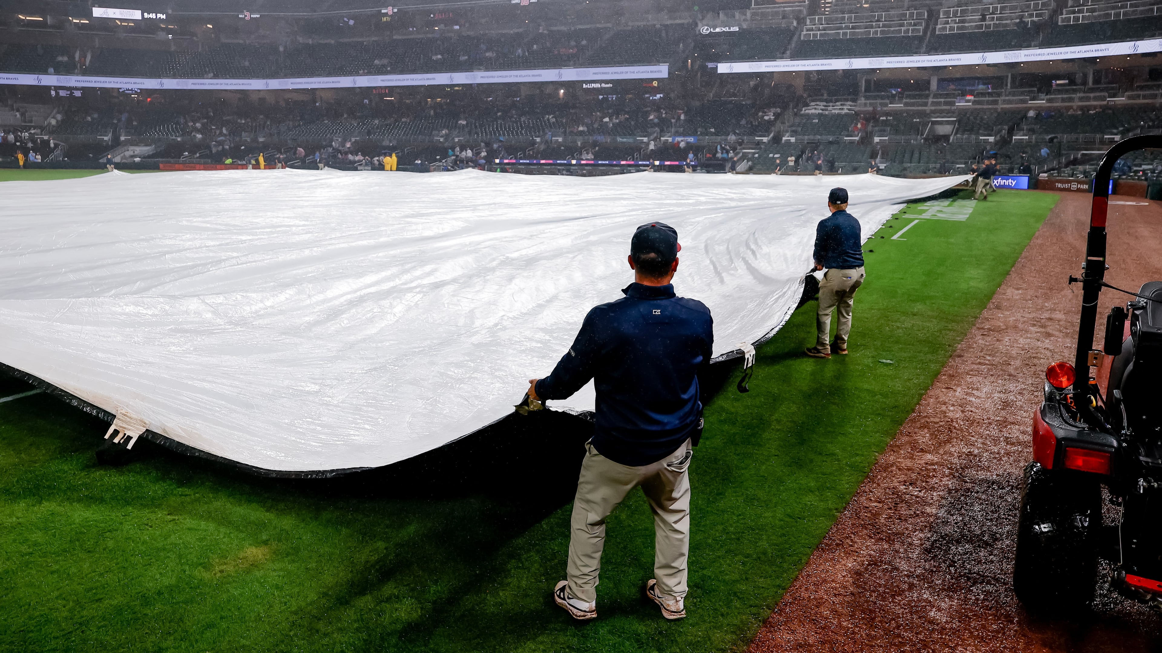 Atlanta Braves grounds crew cover the infield with a tarp after the game was suspended due to weather in the second inning of a baseball game, Tuesday, June 16, 2026, in Atlanta. (AP Photo/Erik S. Lesser)