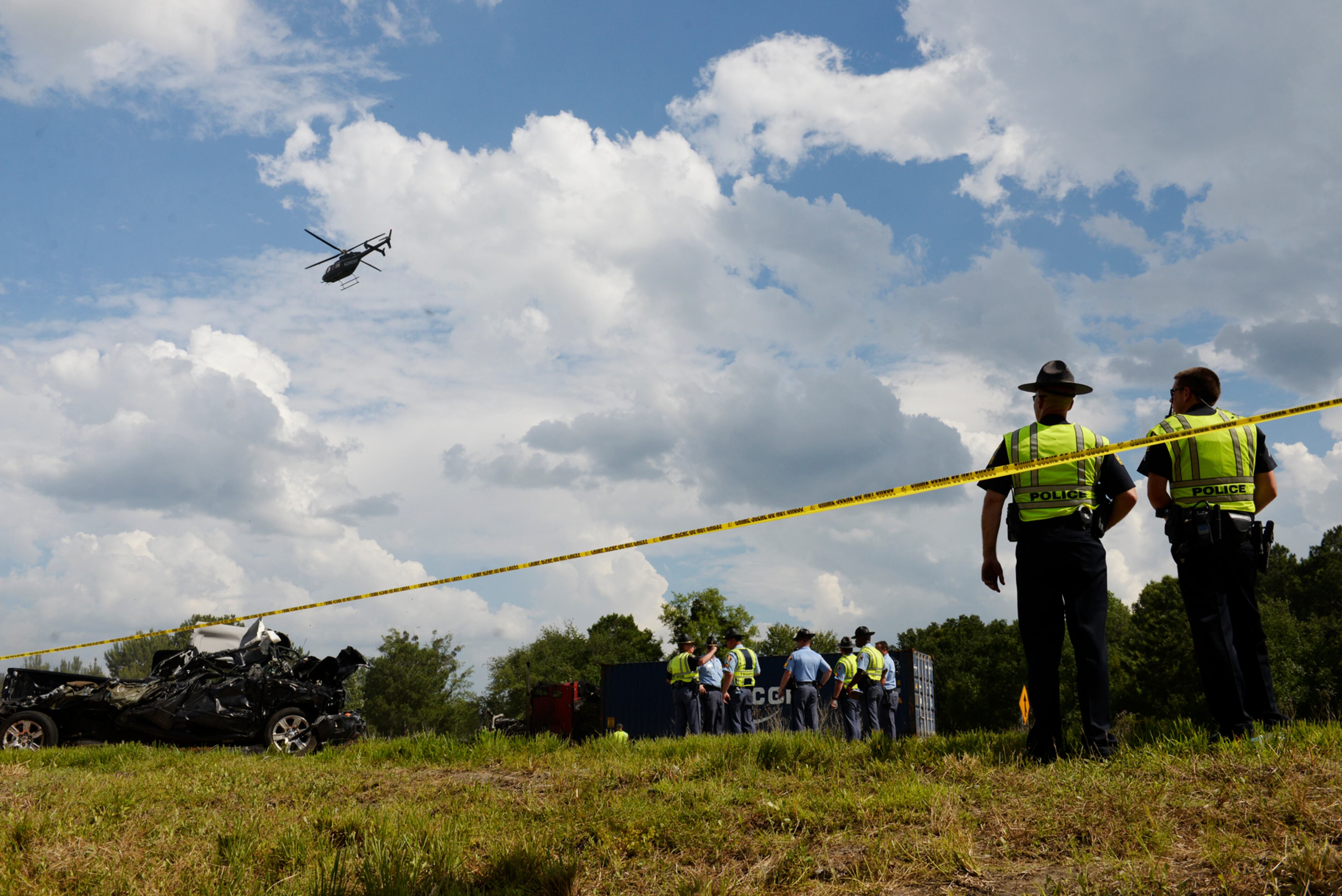 Police officers watch as a helicopter takes aerial photos of a car wreck involving multiple cars and tractor trailers on I-16 in Pooler, Ga. on Tuesday, May 19, 2015. (Ian Maule/Savannah Morning News via AP)