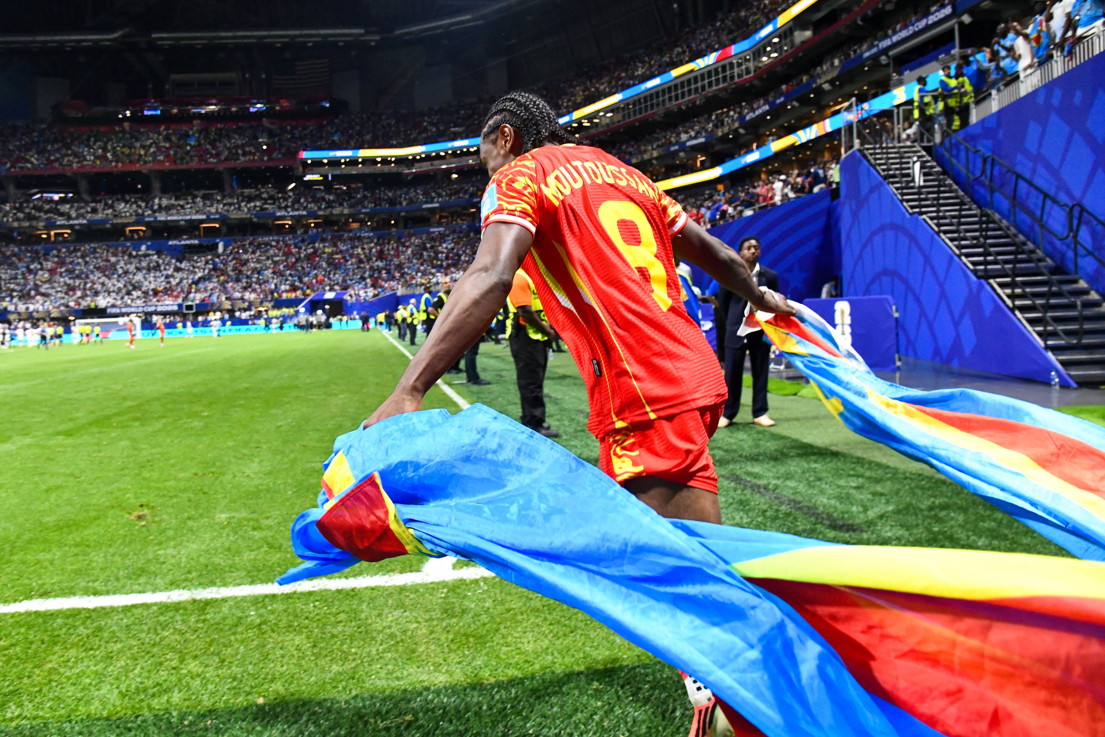DR Congo midfielder Samuel Moutoussamy (8) carries the country flag onto the pitch during the second half of a FIFA World Cup match at Atlanta Stadium (Mercedes-Benz Stadium) on Saturday, June 27, 2026, in Atlanta. (Hyosub Shin/AJC)