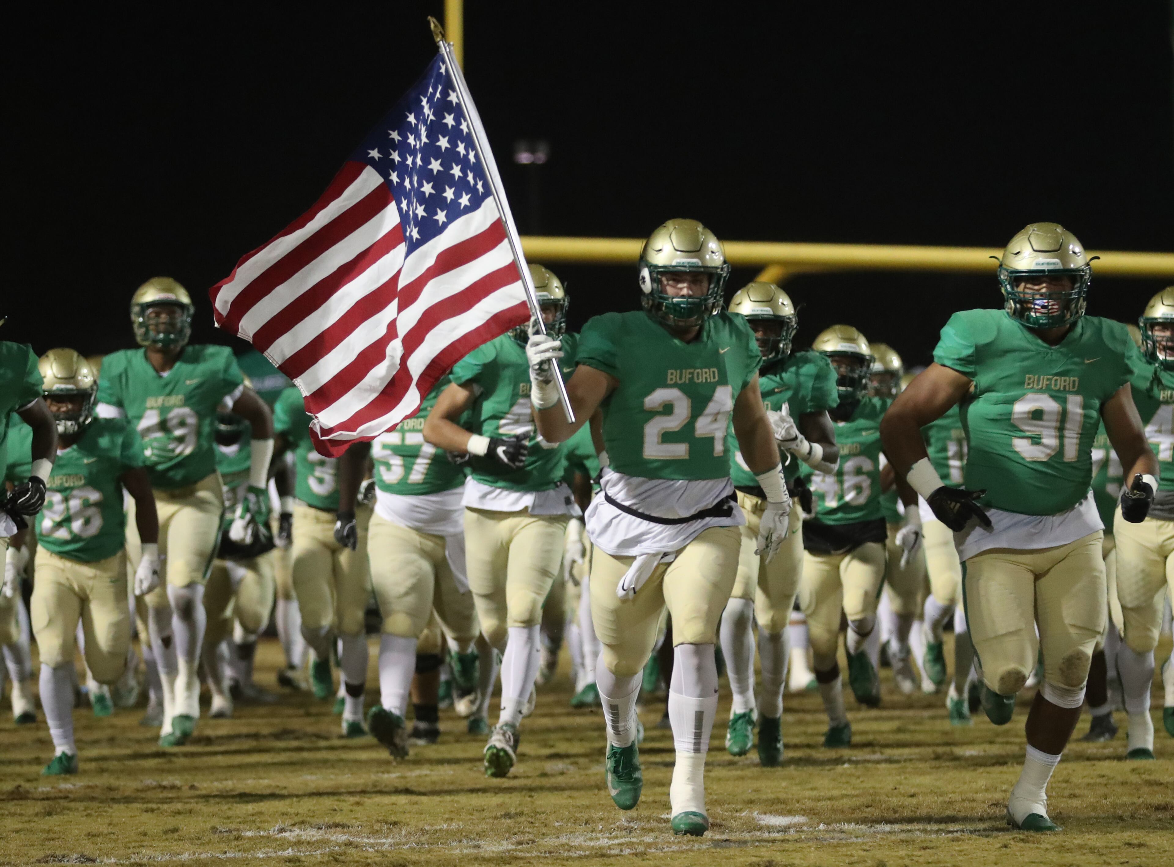 November 23, 2018 - Buford, Ga: Buford linebacker Jack Scroggs (24) carries the U.S. flag onto the field before their game against Bainbridge at Buford High School Friday, November 23, 2018, in Buford, Ga. This is the quarter finals of the Class 5A state playoffs. (JASON GETZ/SPECIAL TO THE AJC)