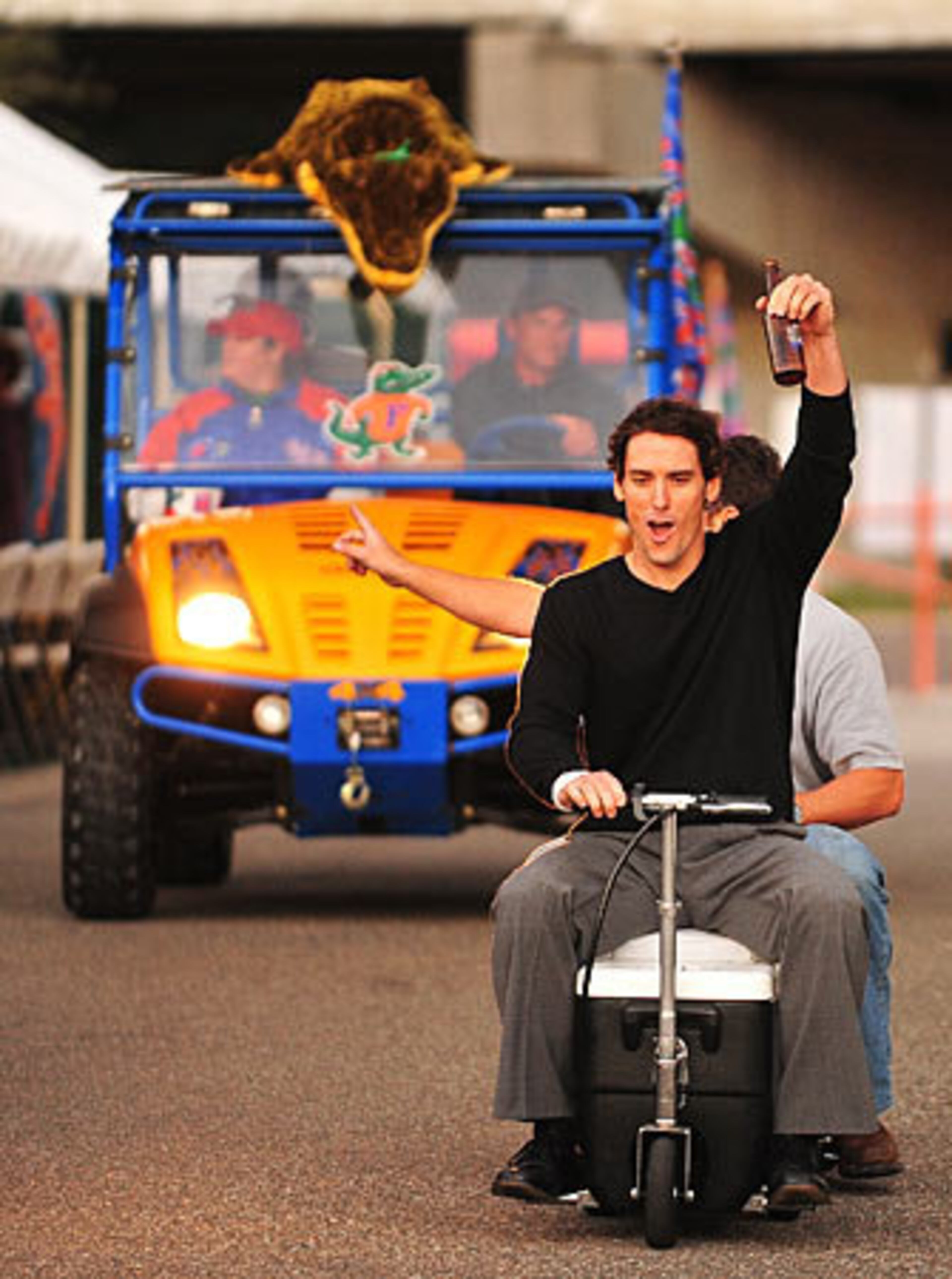 David Fulford of Jacksonville shouts "Go Gators" while navigating his motorized-cooler with another Gator-rooting fan in tow. Behind them is a slightly more upscale Florida fan in a high powered Gator golf cart.