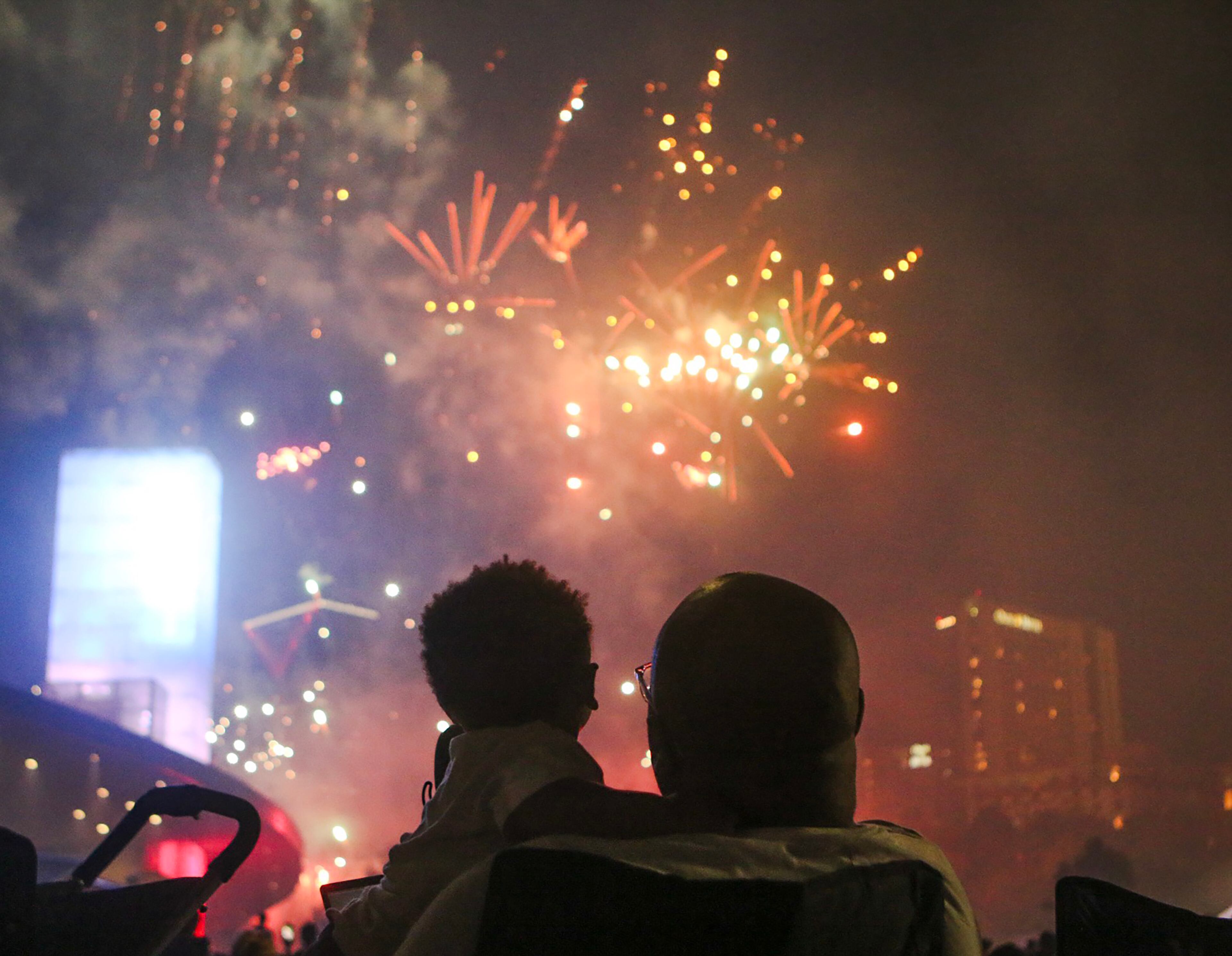 A man holds a child while they watch fireworks at Centennial Olympic Park in Atlanta on Thursday. The fireworks show, part of the annual Fourth of July celebration, was sponsored by the Georgia World Congress Center Authority and Coca-Cola. Christina Matacotta/Christina.Matacotta@ajc.com