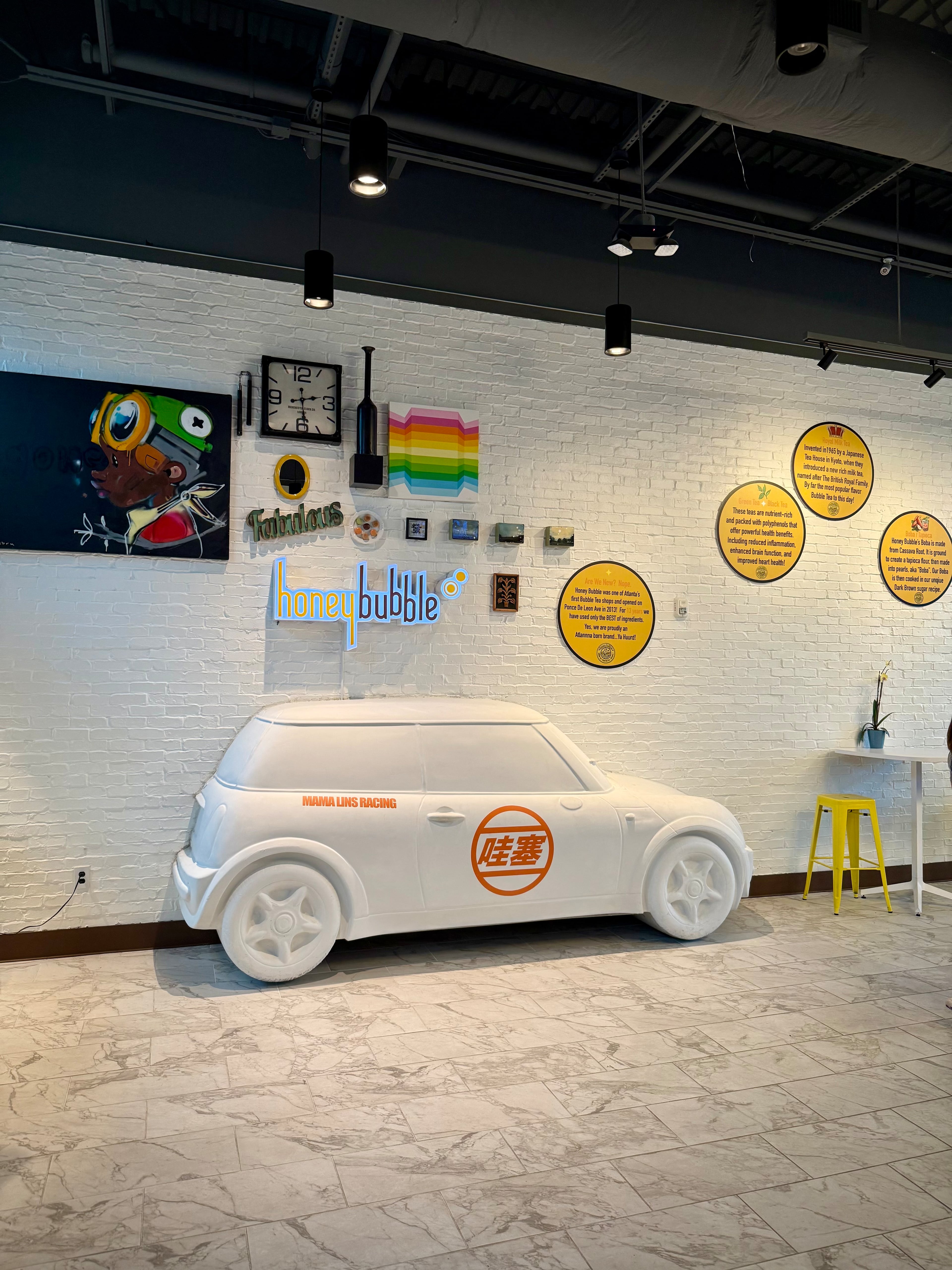 The interior of Honey Bubble and Mama Lin’s Chicken Delight is decorated with colorful pop art-style wall pieces and a life-size sculpture of a Mini Cooper protruding from the wall. (Henri Hollis/AJC)