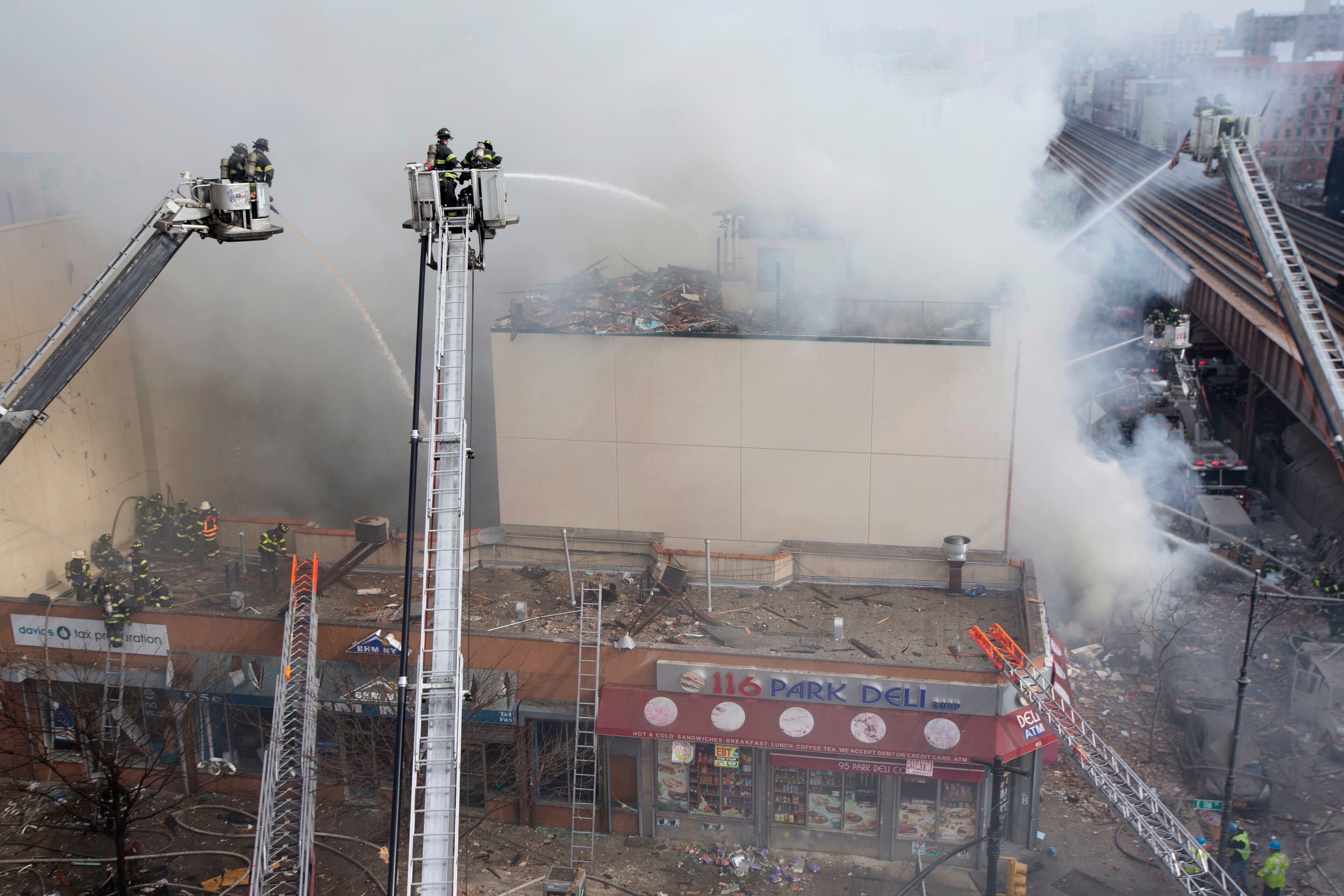 Firefighters respond to a fire after an explosion and building collapse in the East Harlem neighborhood of New York, Wednesday, March 12, 2014. The explosion leveled an apartment building, and sent flames and billowing black smoke above the skyline. (AP Photo/John Minchillo)