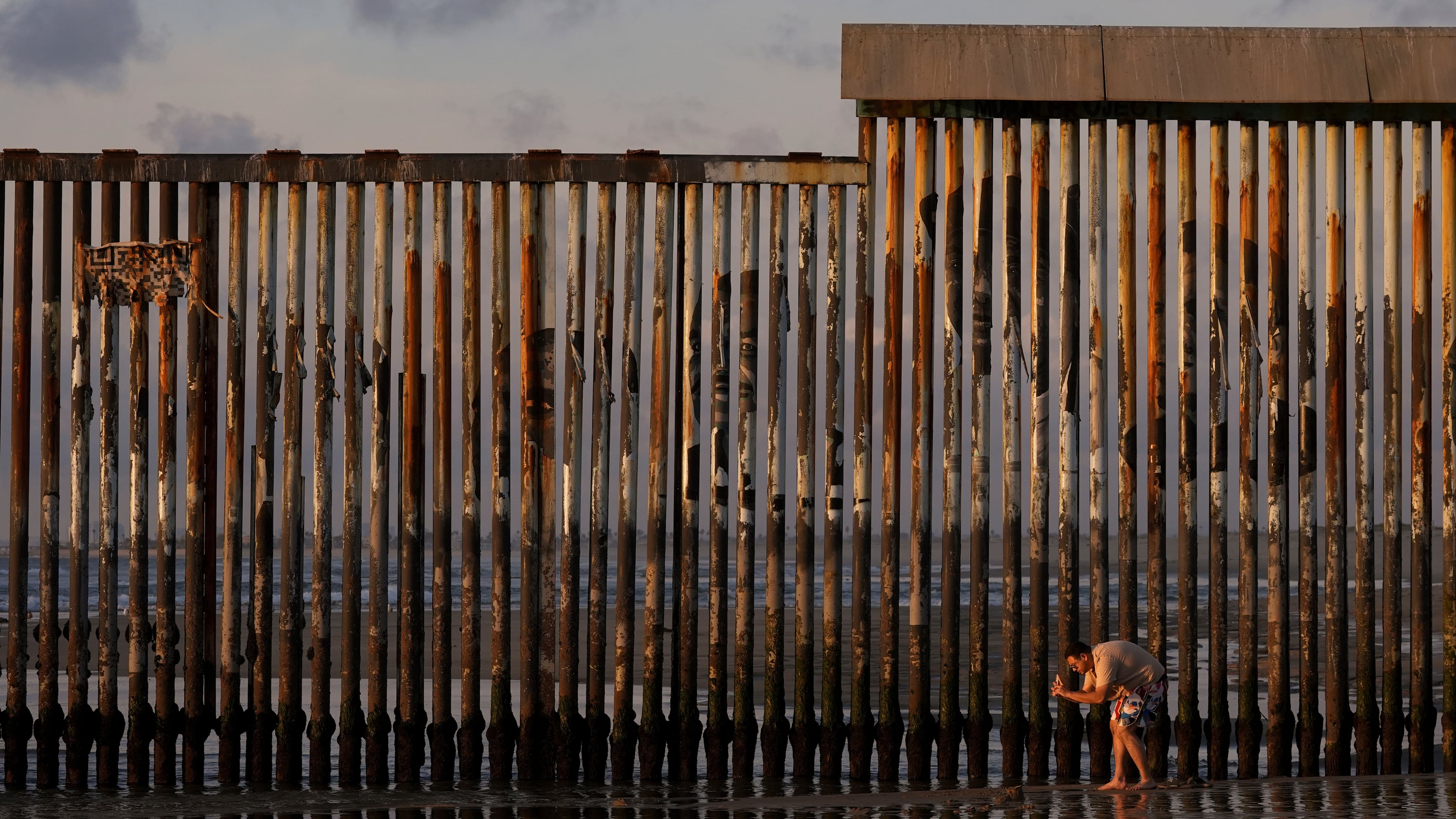 FILE - A man takes an image with his phone next to where the border wall separating Mexico and the United States reaches the Pacific Ocean Jan. 28, 2025, in Tijuana, Mexico. (AP Photo/Gregory Bull, File)