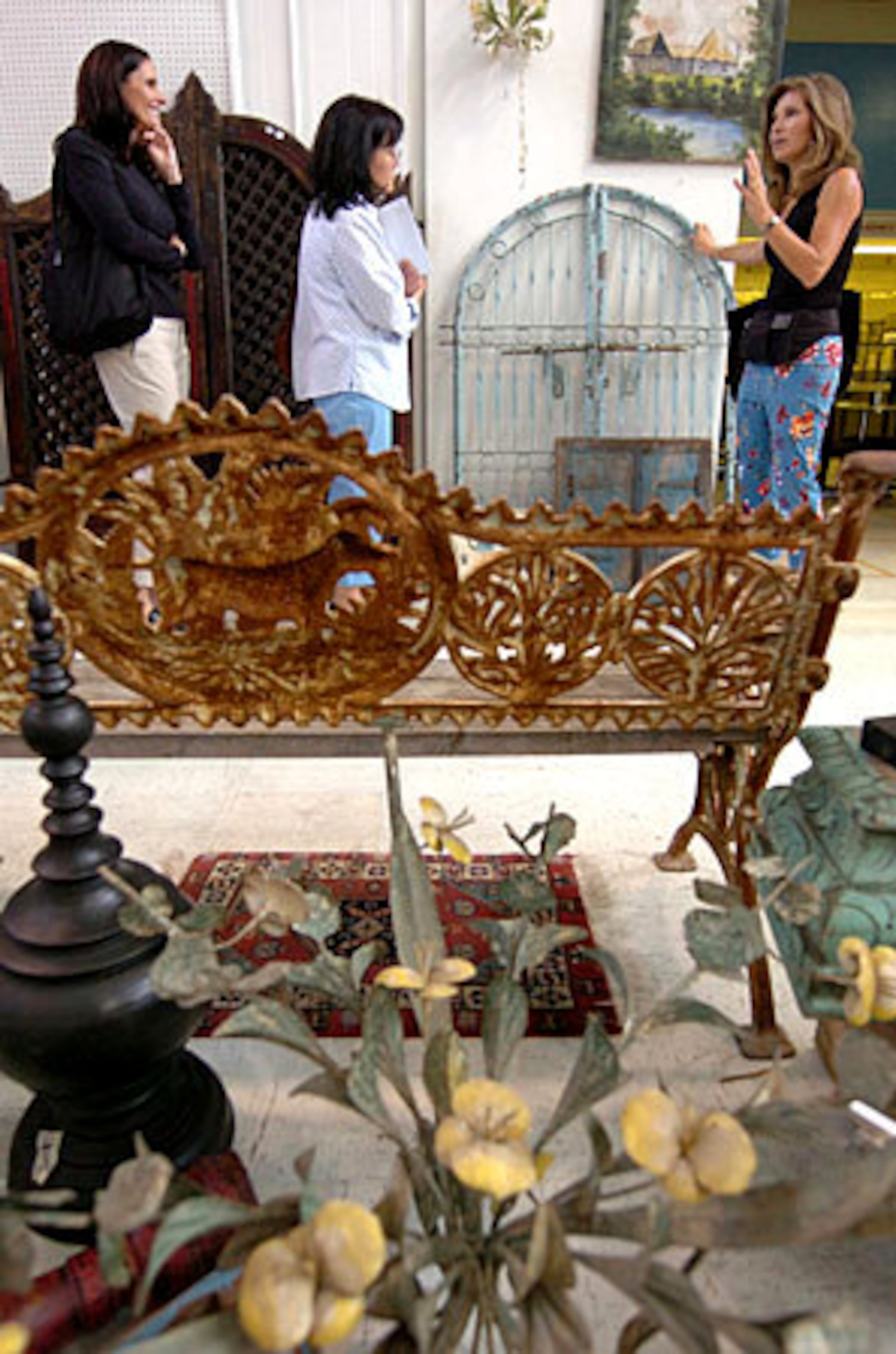 Duvall Fuqua (left,) and Laura Iarocci (center) listen as Christine Eisner discusses the door and gate they discovered at Scott Antique Market. Eisner, a designer, helps clients navigate the massive market to find good deals.
