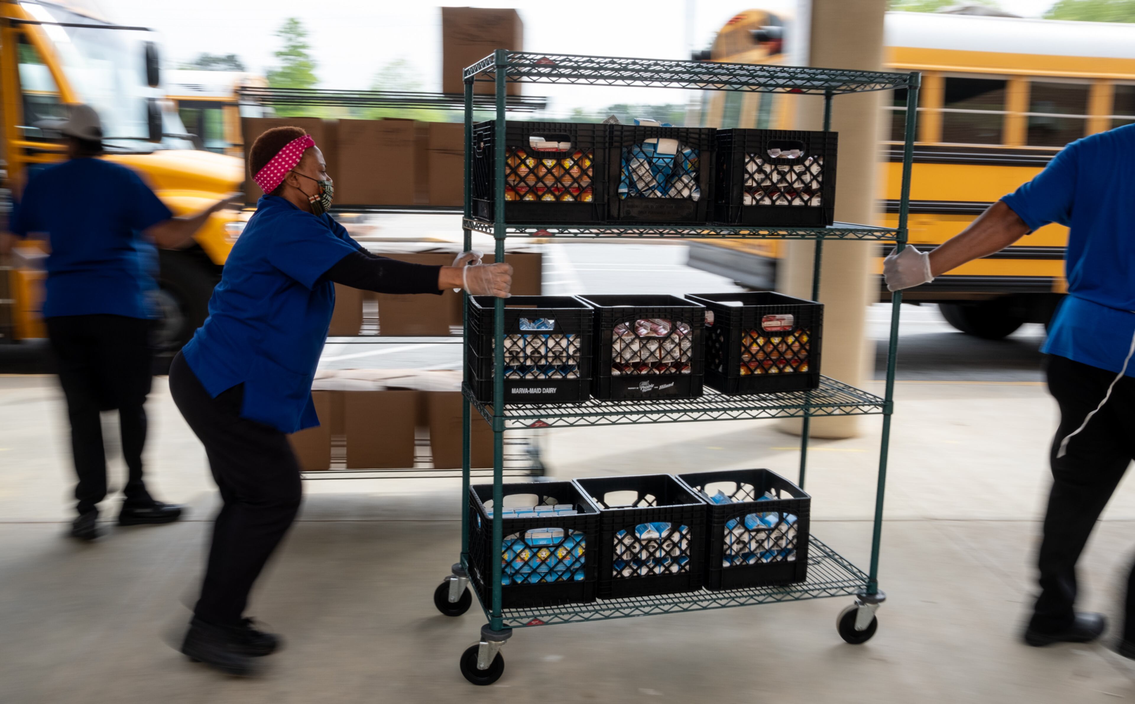 200407-Lilburn-Gwinnett County cafeteria workers bring freshly prepared food out to waiting school buses in front of Berkmar High School so they can be delivered to students around the district on Tuesday morning April 7, 2020. Ben@BenGray.com for the Atlanta Journal-Constitution