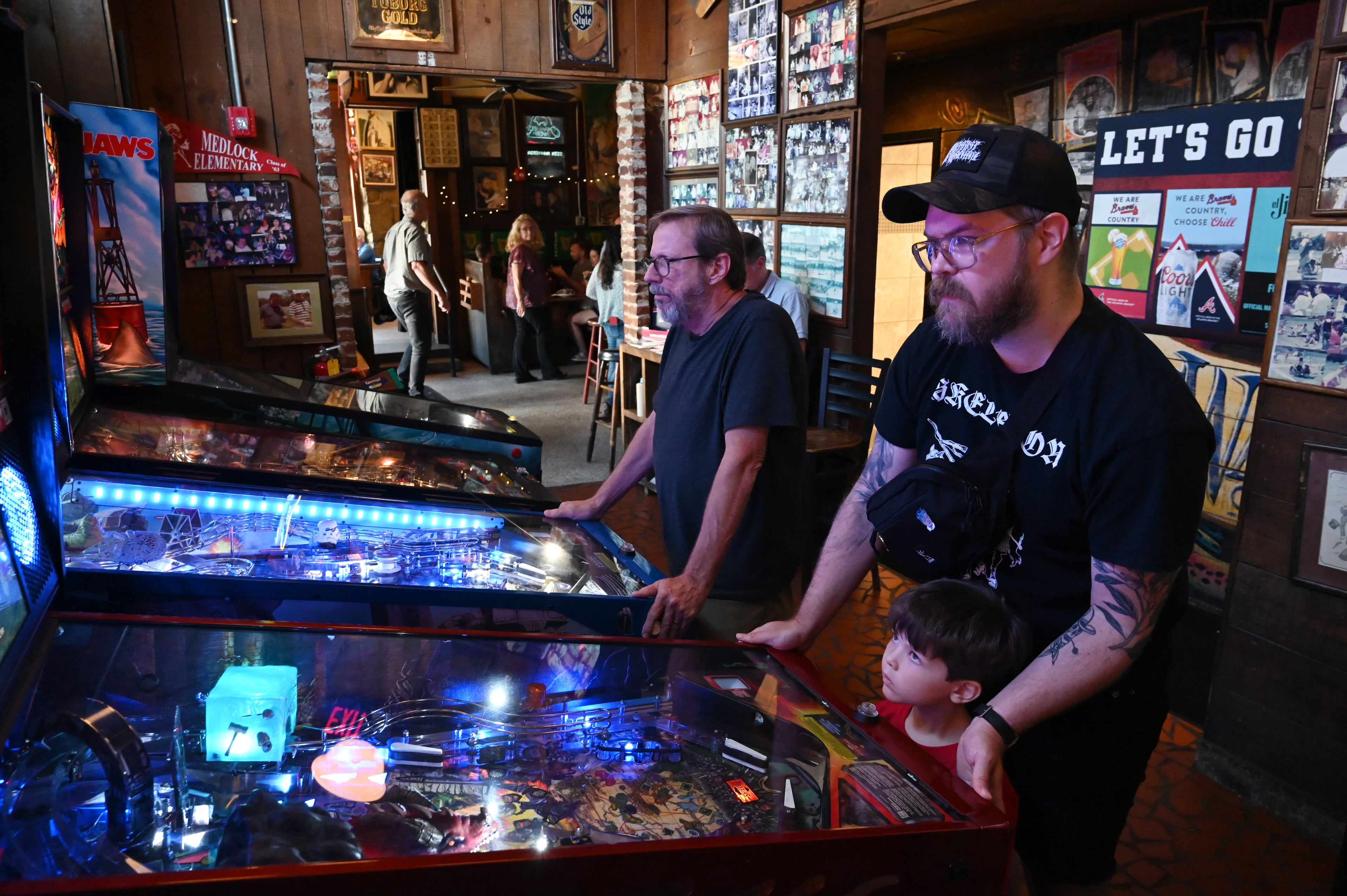 Travis Parkman (right) and his son Wyatt, 3, play a Plinko-style game as Manuel’s Tavern celebrates its 70th anniversary on Thursday, Aug. 6, 2026, in Atlanta. (Hyosub Shin/AJC)