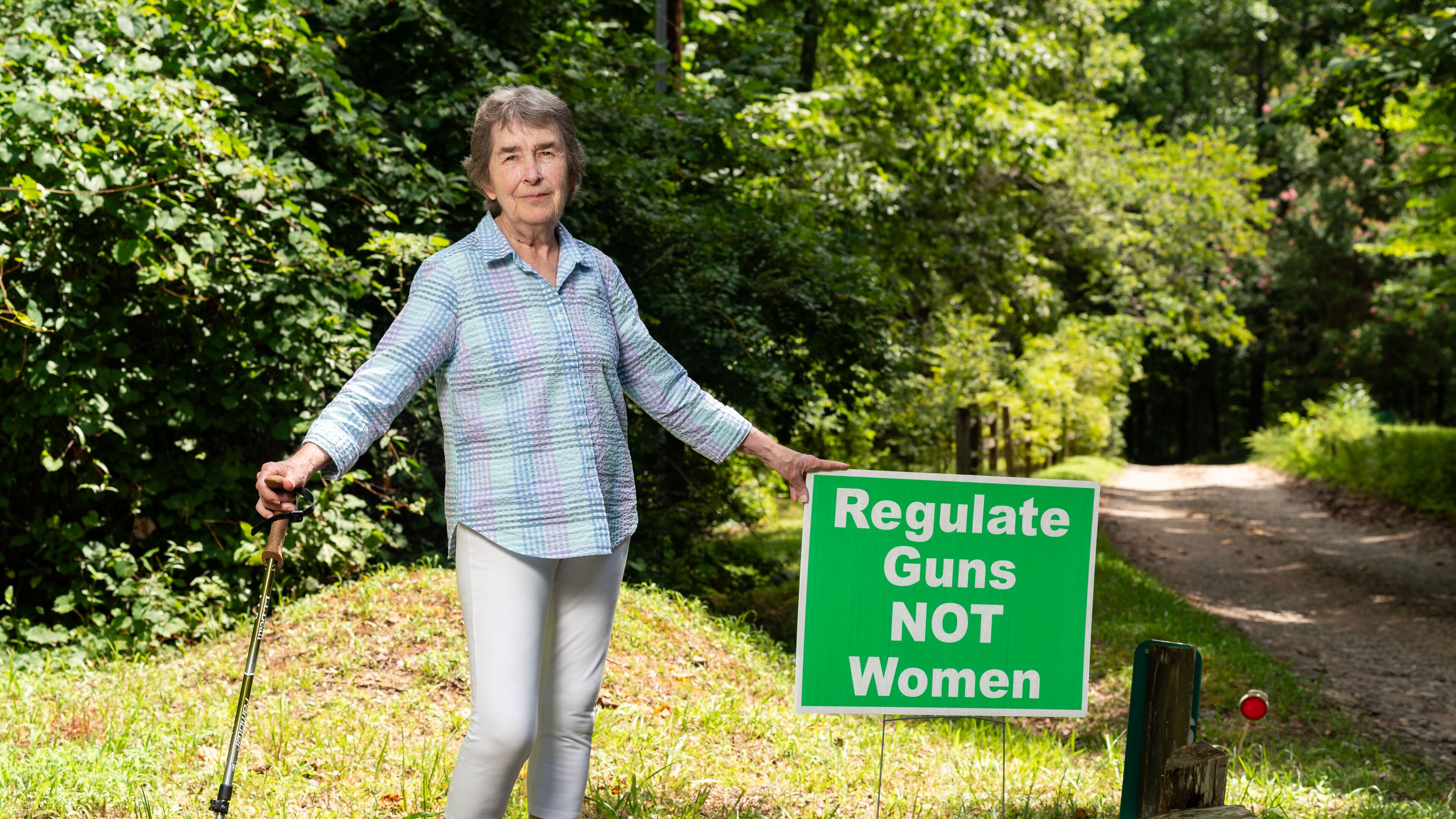 Mary Ellen Myers, a member of the Banks County Democratic Committee, poses with a sign she used to display in her yard in Alto. Myers said she found trash, such as drink cans, thrown at the sign, although she's faced little other backlash. “There’s some civility in this county,” said Myers, who has lived in Banks County for more than two decades. (Seeger Gray / AJC)