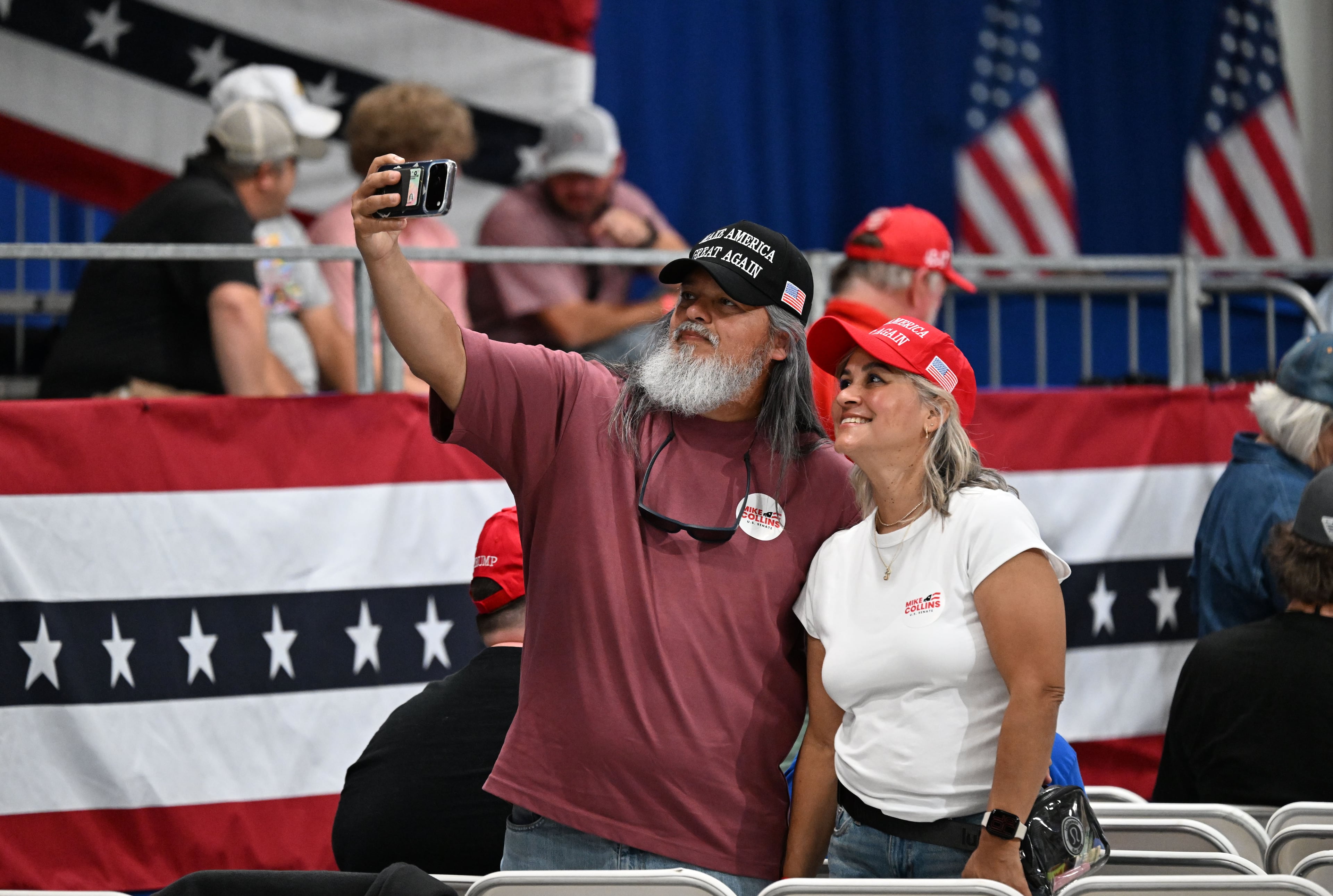 Attendees take a selfie as they arrive for a midterm campaign rally at Guardian Centers on Saturday, Oct. 24, 2026, in Perry. (Hyosub Shin/AJC)