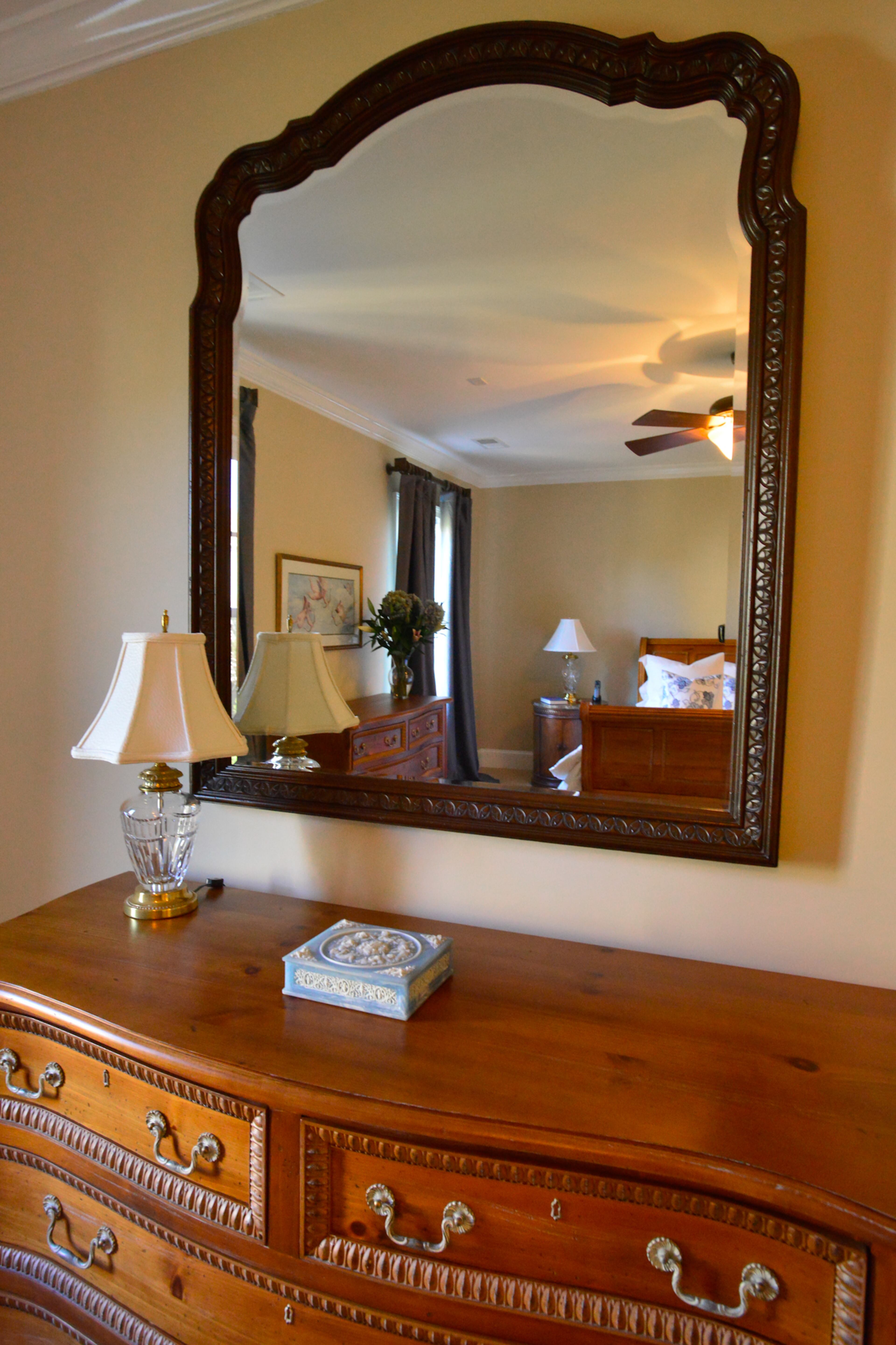 A mirror hangs over a pine dresser, which was part of a set of furniture by Century Furniture. The set also includes the dining room table and credenza, living room coffee table and side tables, the master bedroom bed and bedside tables, and a demilune chest in the foyer.