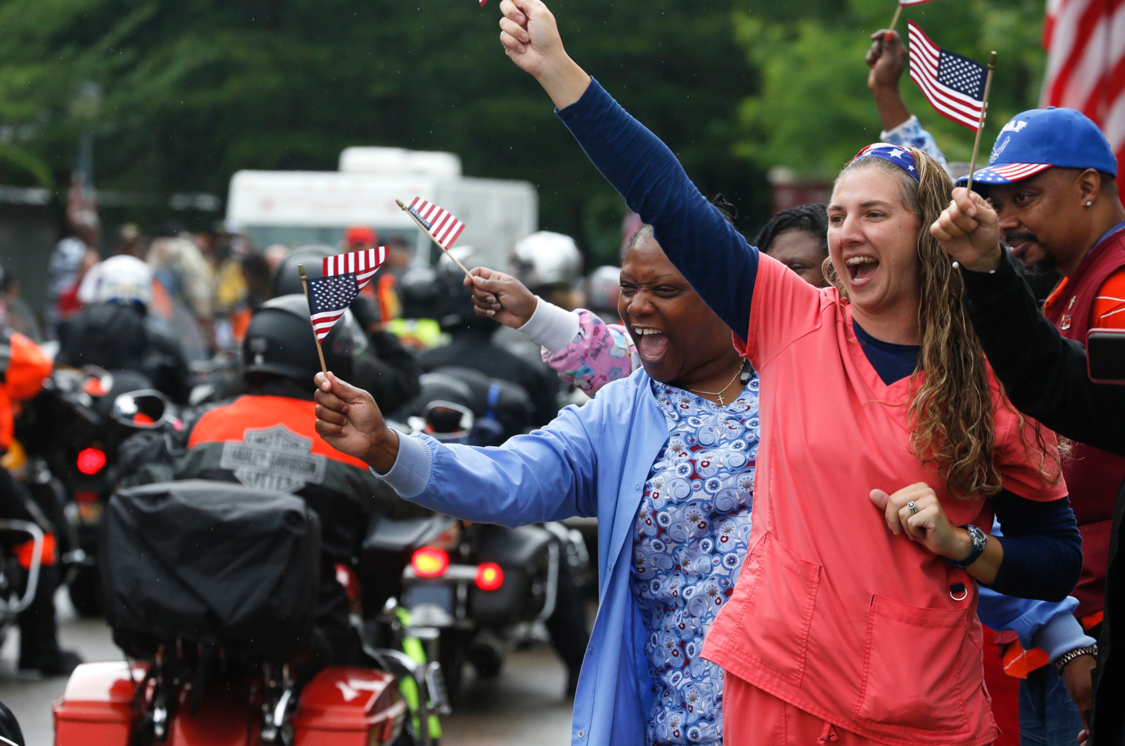 Motorcyclists in Run for the Wall cruise in to the Tuscaloosa Veterans Administration Medical Center for the 17th consecutive year Tuesday, May 23, 2017. The riders are on their way from California to the Vietnam Wall in Washington, D.C., for Memorial Day. Nurses Patricia Banks, left, and Erica Quimby, right, wave flags and yell welcomes to cyclists arriving at the V.A. (Gary Cosby Jr./The Tuscaloosa News via AP)