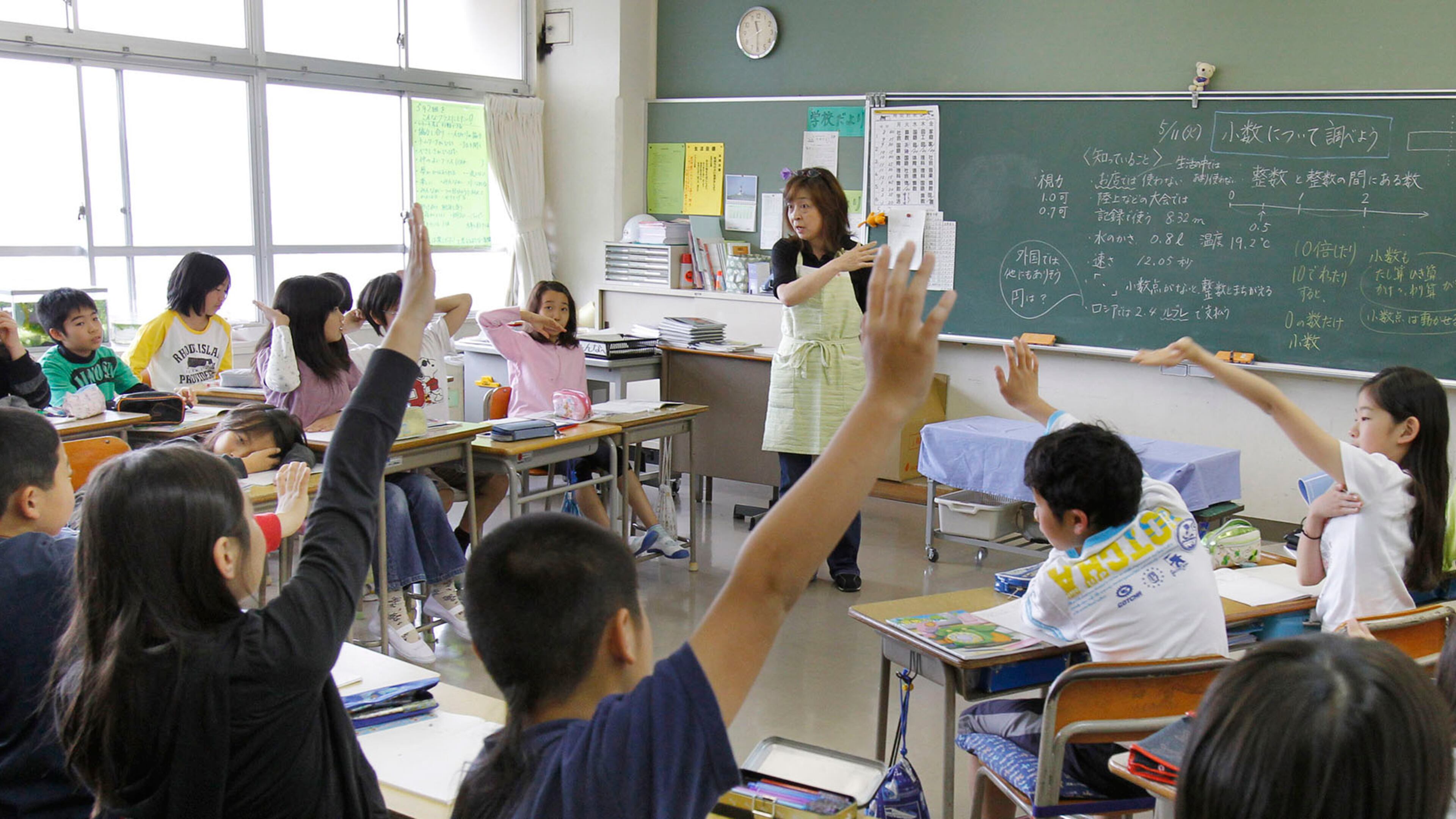 Students at a school in Yokohama, Japan, raise their hands for a math question.