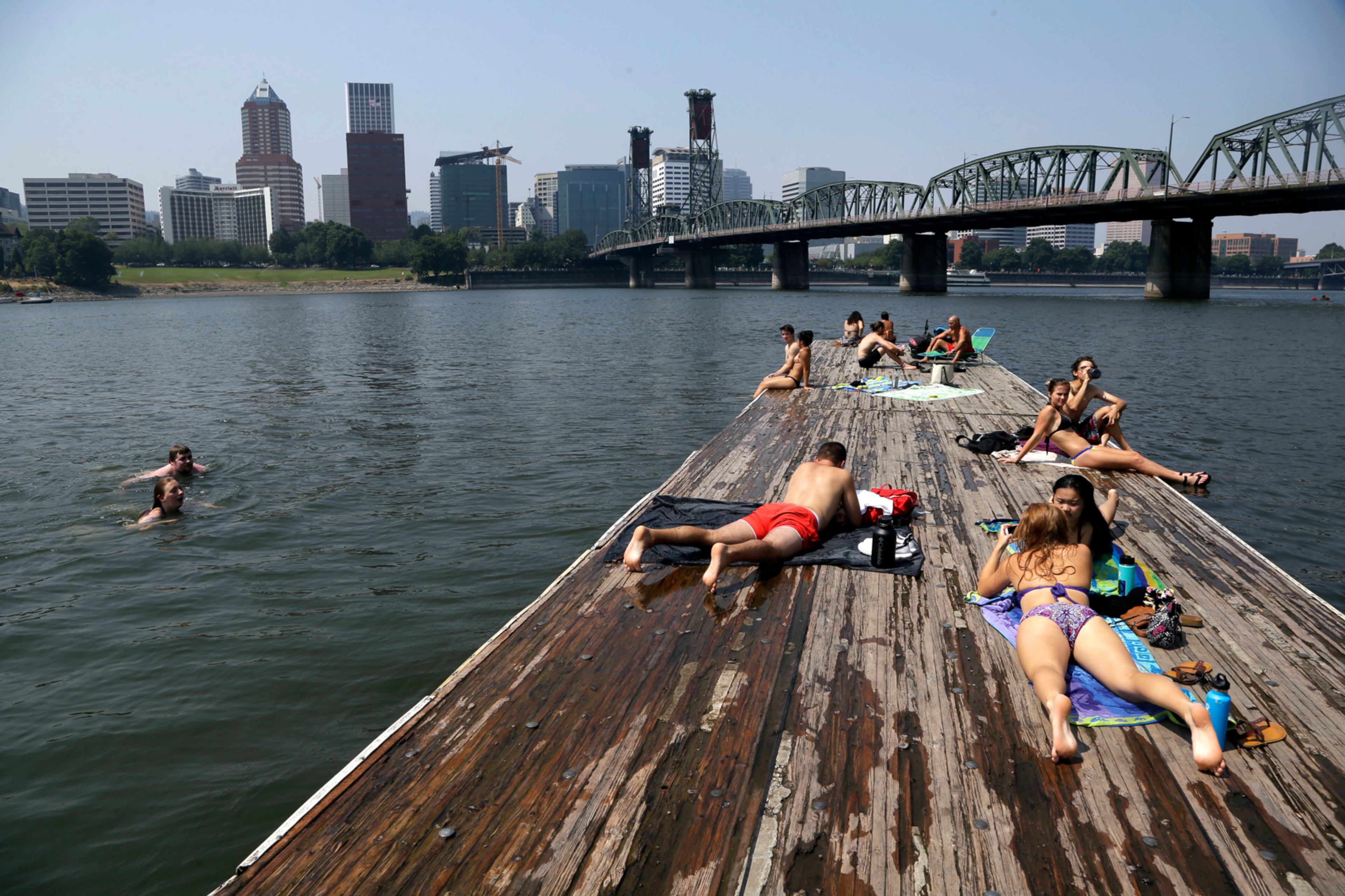 People sunbathe and cool off in the Willamette River with the downtown skyline visible in the background in Portland, Ore., Wednesday, Aug. 2, 2017. Scorching temperatures are predicted for the Northwest Wednesday and Thursday, with forecasters saying Seattle and Portland could top triple digits and break records. (AP Photo/Don Ryan)