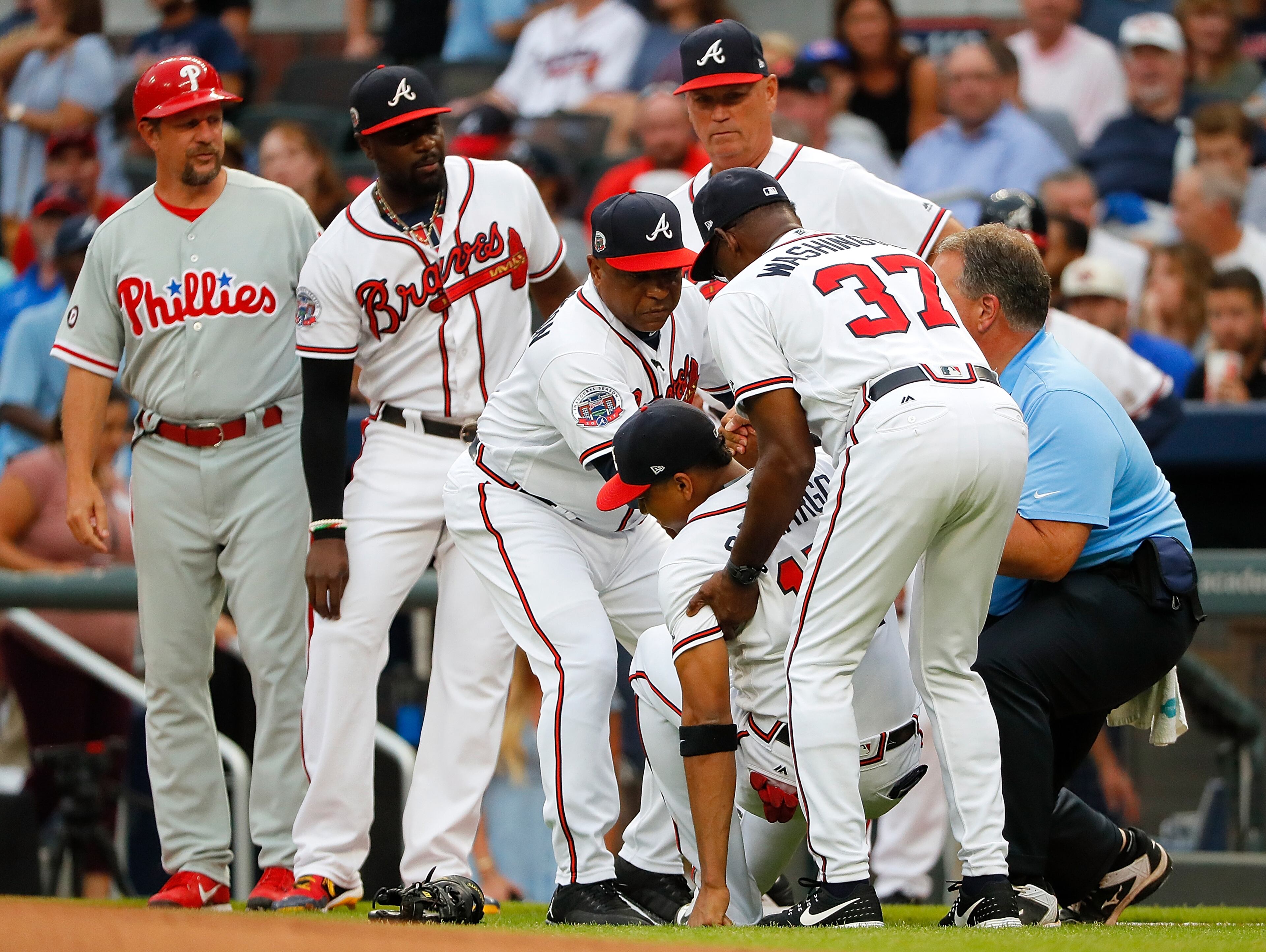 ATLANTA, GA - AUGUST 08: Bench coach Terry Pendleton #9, third base coach Ron Washington #37 and trainer Jim Lovell of the Atlanta Braves help up Johan Camargo #17 after he fell to the ground running onto the field in the first inning to face the Philadelphia Phillies at SunTrust Park on August 8, 2017 in Atlanta, Georgia. (Photo by Kevin C. Cox/Getty Images)