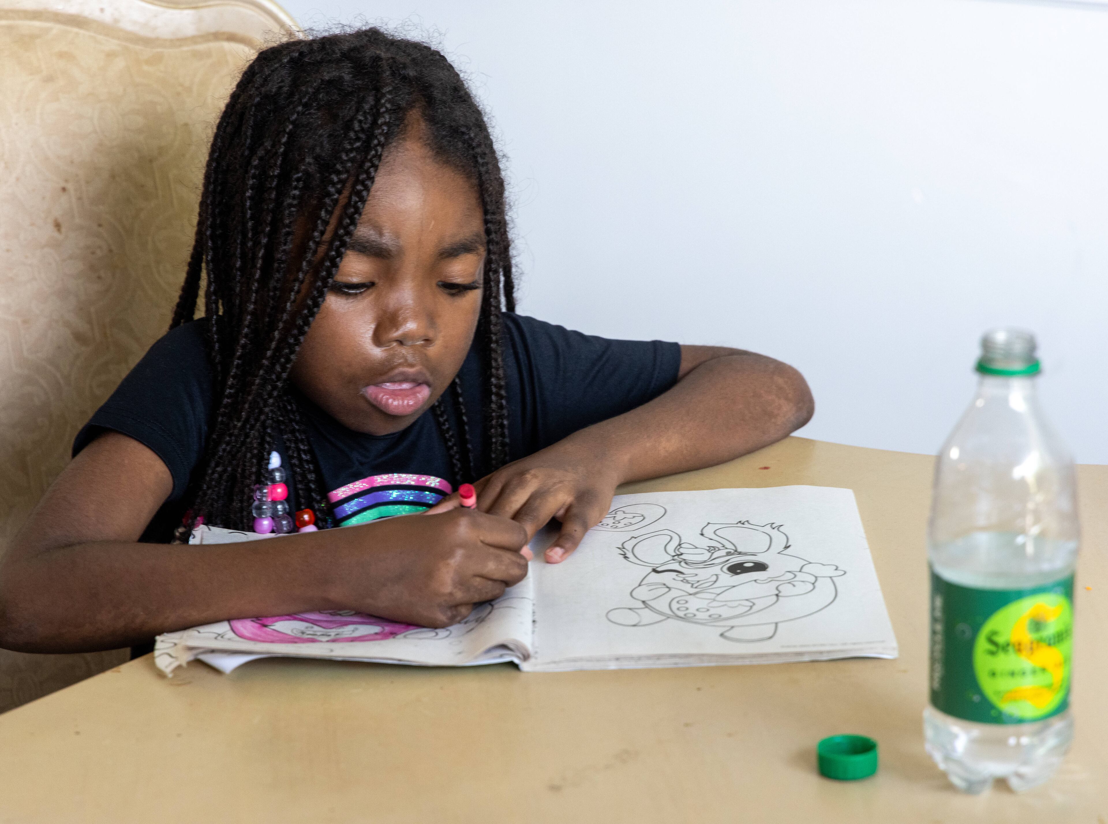 J'Adore Sledge colors as her mother Ebon Sledge helps her siblings with their homework in their new rental home in metro Atlanta. PHIL SKINNER FOR THE ATLANTA JOURNAL-CONSTITUTION