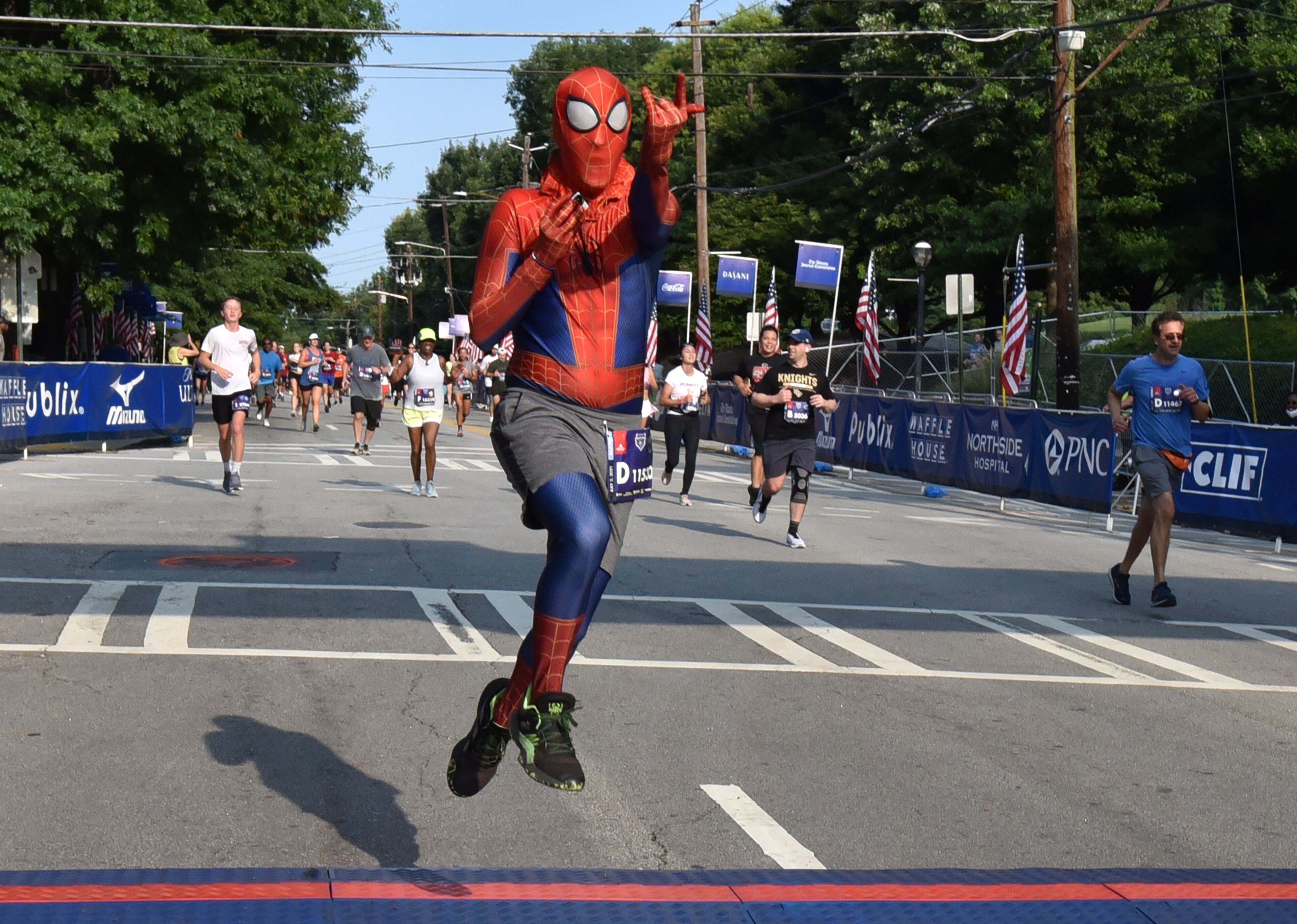July 3, 2021 Atlanta - A runner with spider man costume gestures as he crosses the finish line during the first day of 2021 Atlanta Journal-Constitution Peachtree Road Race on Saturday, July 3, 2021. (Hyosub Shin / Hyosub.Shin@ajc.com)