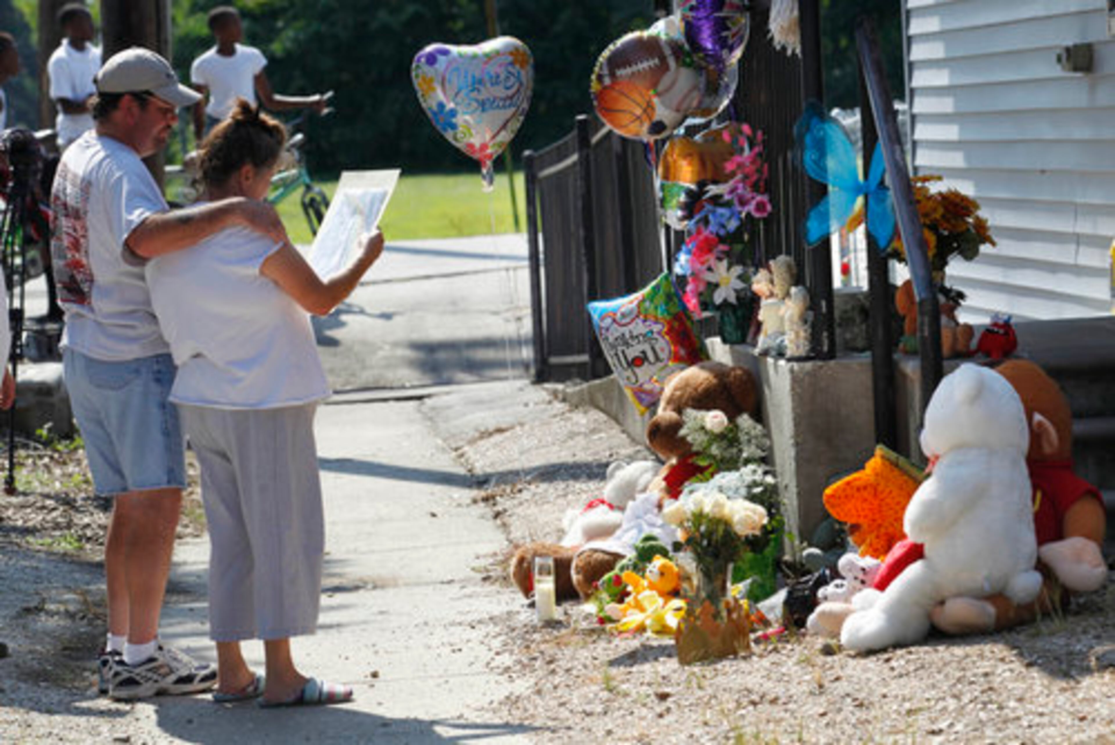A LIFE GONE TOO SOON--Deline and Barry Himel, grandparents of seven year old Jori Lirette, who was disabled and wheelchair bound from cerebral palsy, and was found decapitated and dumped outside his home, read a letter amongst mementos left outside the home in Thibodaux, Monday, Aug. 15, 2011. Jeremiah Lee Wright, 30, father of the child, has confessed to killing him, Thibodaux Police Chief Scott Silverii said Monday.