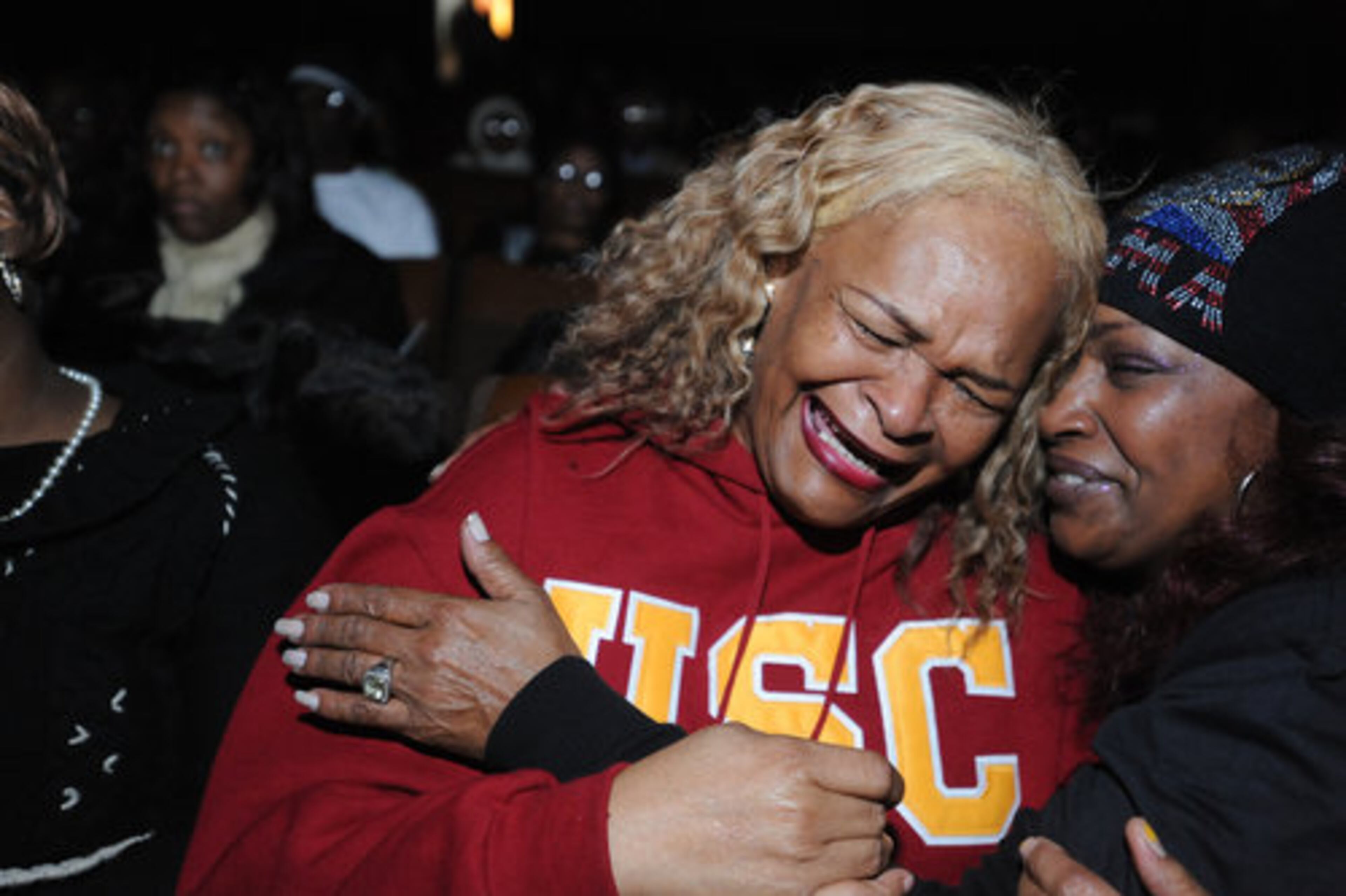 Sassc Shakoor (right) comforts her friend Ann Gardner (center) as Gardner bursts into tears as they watch the historic inauguration of Barack Obama at the Torch theater in Lithonia.