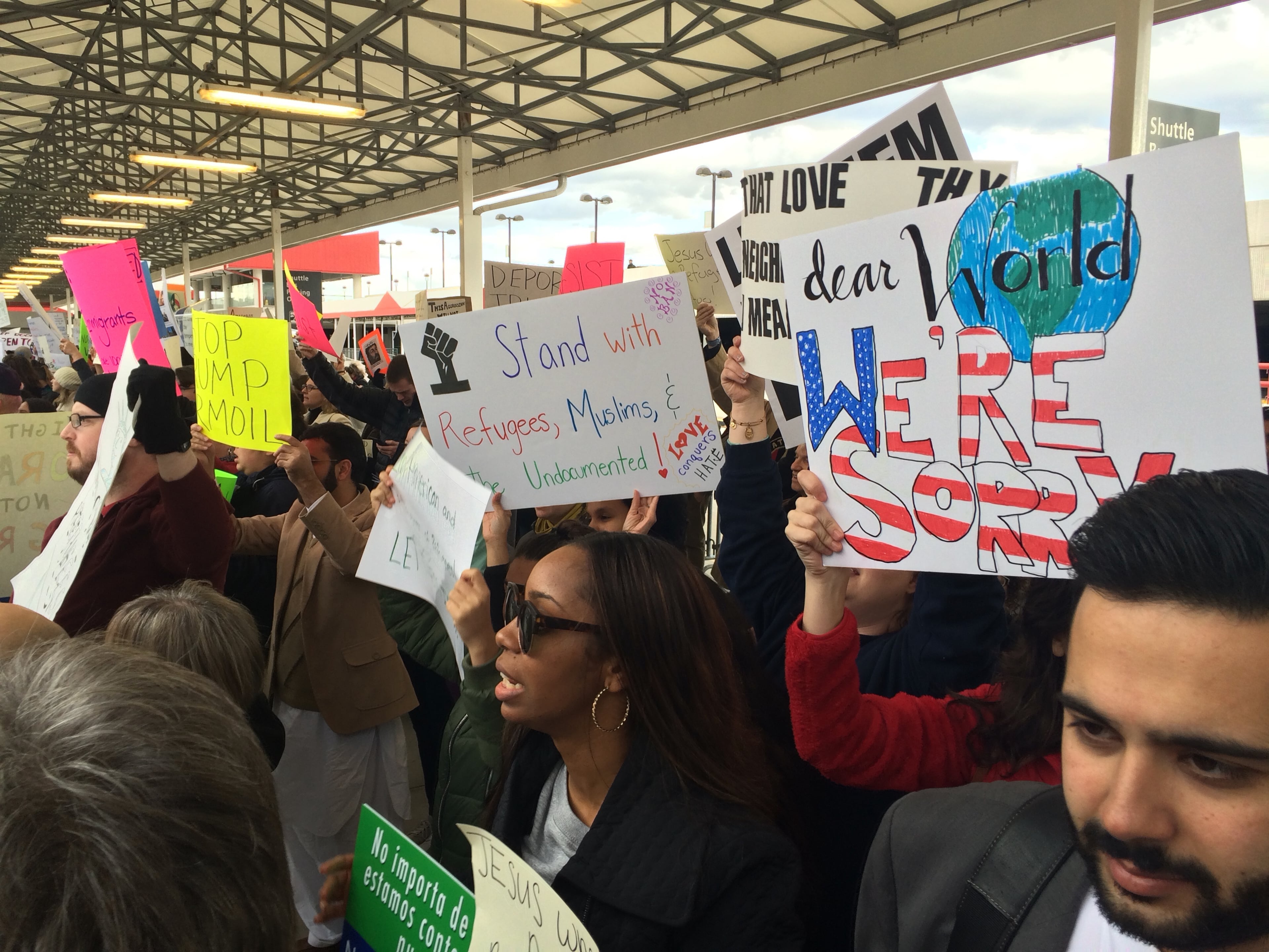 Protesters carry signs Sunday at Atlanta Hartsfield-Jackson International Airport. They are protesting new limits on refugees and immigration imposed by President Donald Trump. (Scott Trubey / AJC)