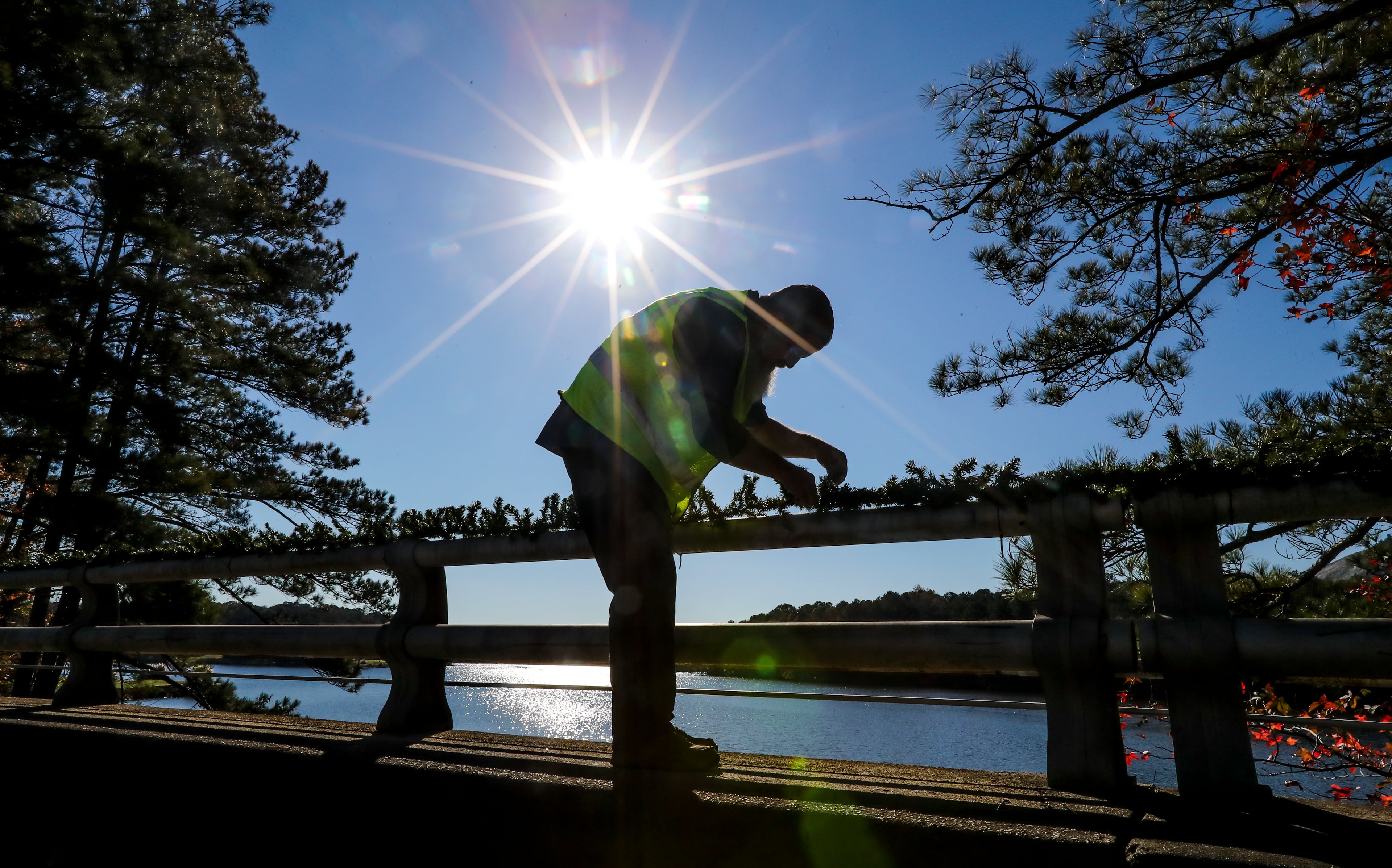 Stone Mountain Park worker, James McGhee (shown here) and crews decorated the bridges spanning over Stone Mountain Lake with Christmas garland on Friday, Nov. 13, 2020. (John Spink / John.Spink@ajc.com)