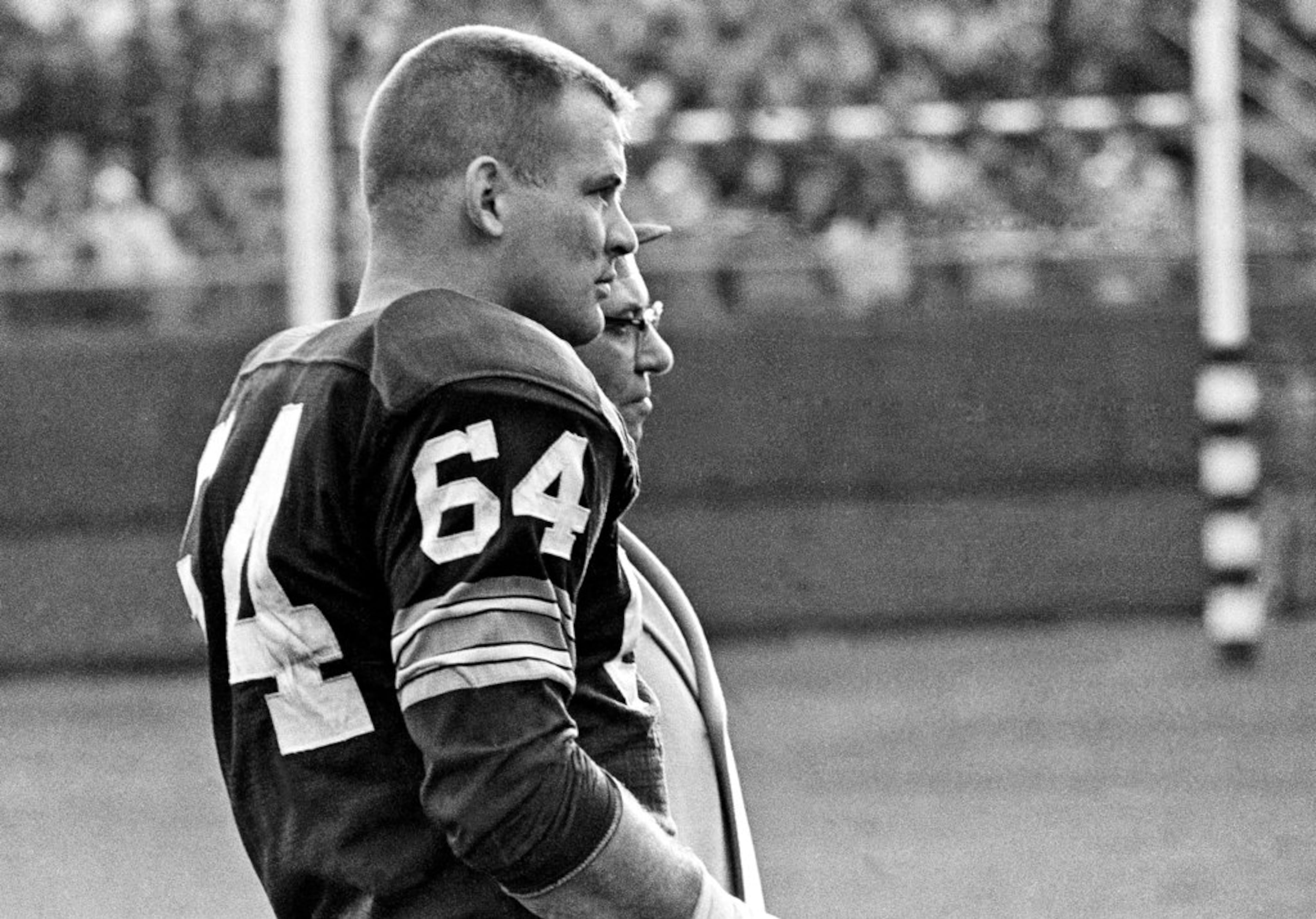 FILE - In this Nov. 24, 1963, file photo, Green Bay Packers offensive guard Jerry Kramer and coach Vince Lombardi watch the Packers' defense against the San Francisco 49ers in an NFL football game in Milwaukee. Kramer was elected to the Pro Football Hall of Fame on Saturday, Feb. 3, 2018. (AP Photo/File)