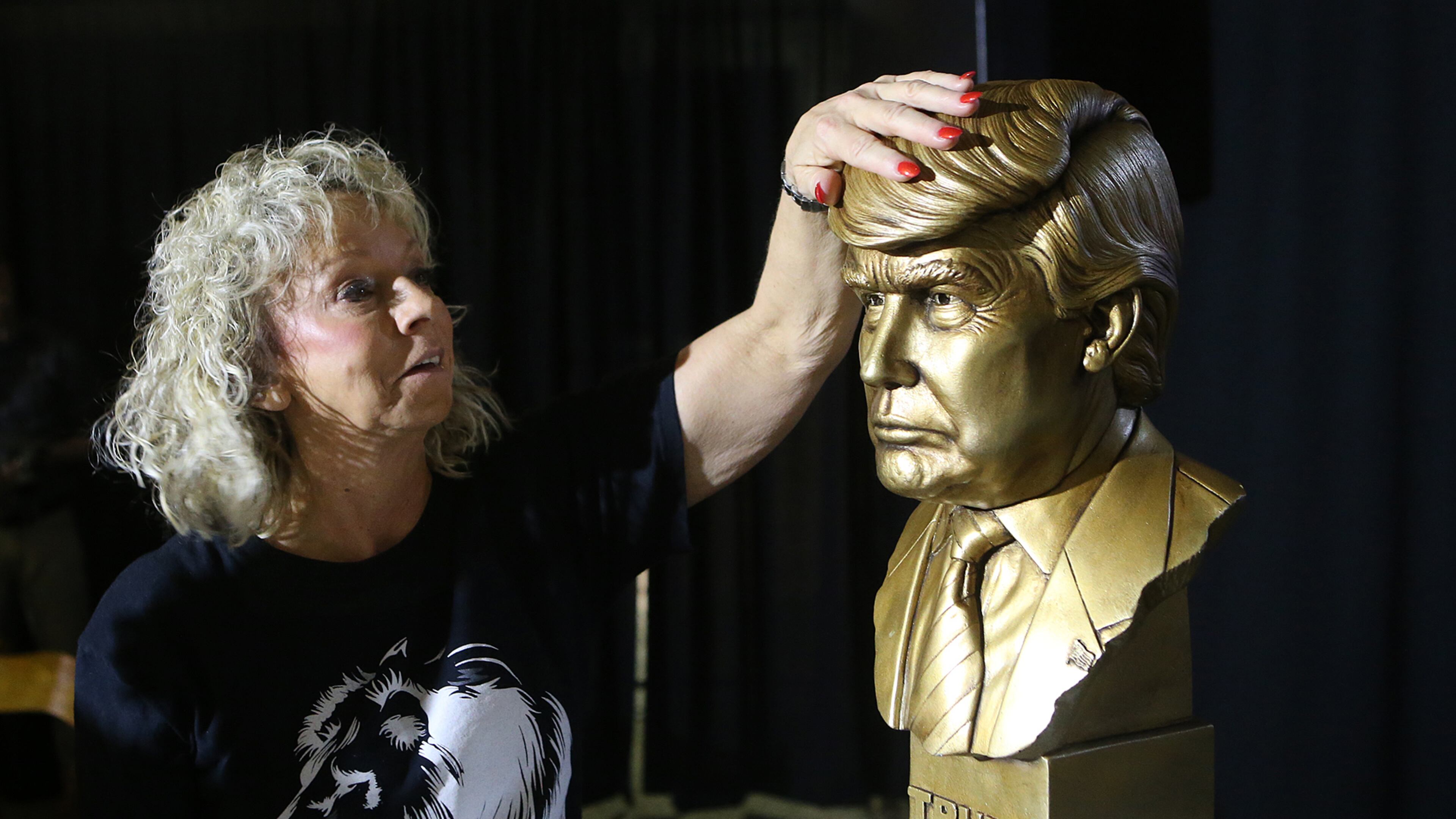 Debbie Dooley, a tea party activist, rubs the brass head of a Donald Trump statue for luck on the stage at the Corey Center during a Trump watch party on Tuesday. Curtis Compton, ccompton@ajc.com