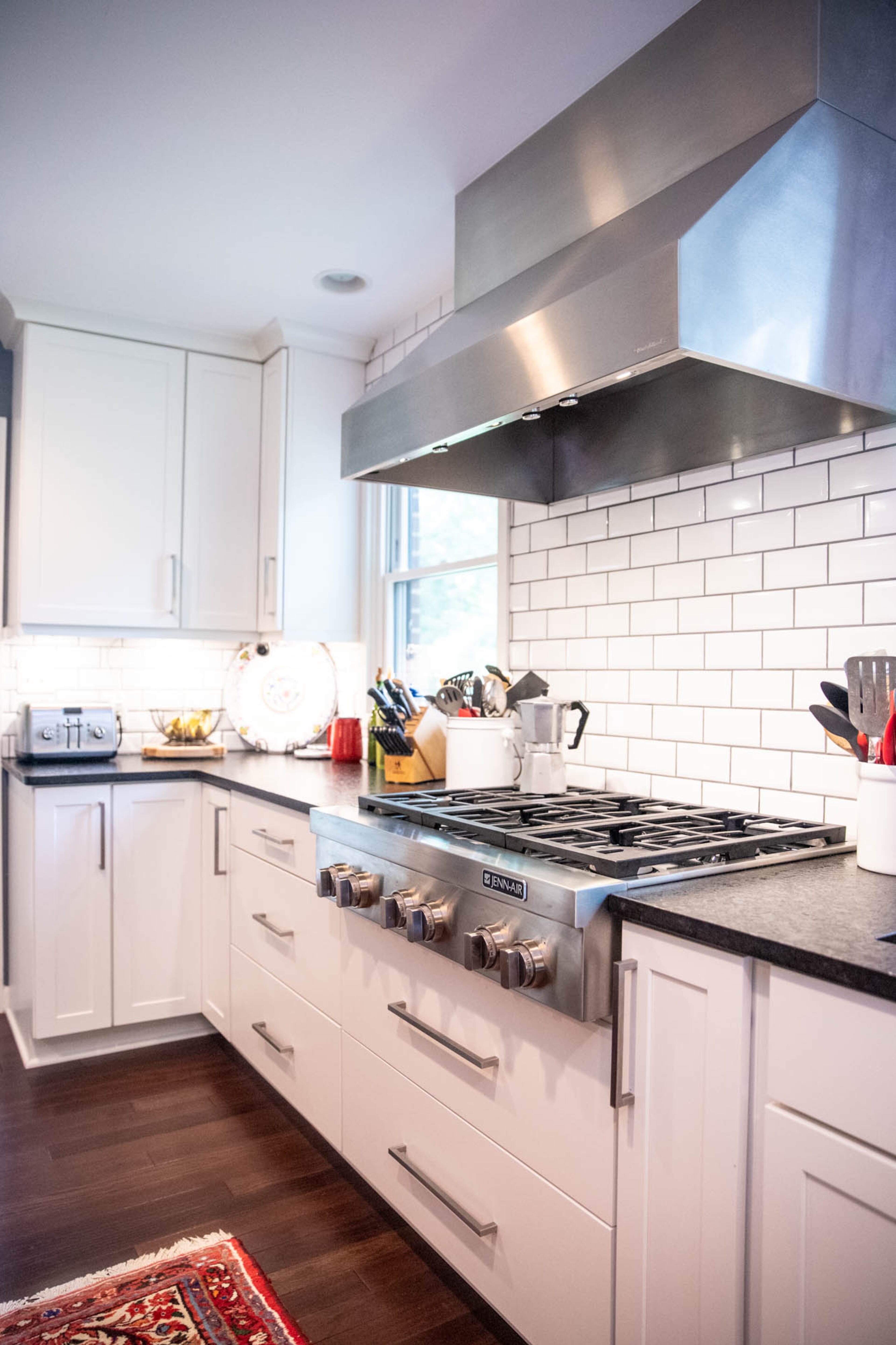 Bright white ice beveled ceramic wall tile by Floor & Decor paired with the perimeter cabinets in maple with an alabaster painted finish by CSI Kitchen & Bath Studio add clean lines to Adam Perry and Ben Ratossa's transitional style kitchen.