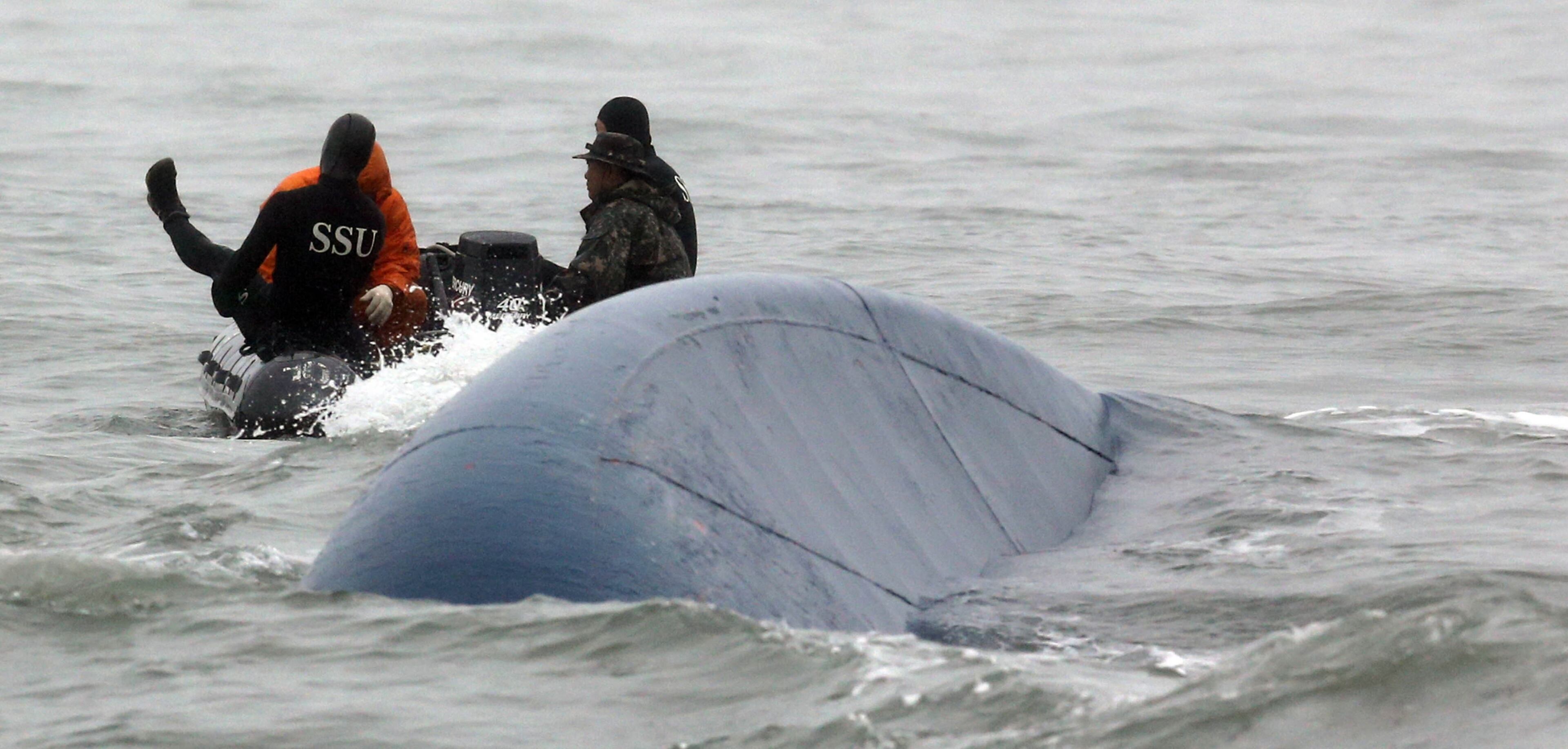 South Korean navy officers try to search missing passengers aboard the Sewol ferry in the water off the southern coast near Jindo, South Korea, Friday, April 18, 2014. The doomed ferry's captain delayed evacuation for half an hour after a South Korean transportation official ordered preparations to abandon ship, raising more questions about whether quick action could have saved scores of passengers still missing Friday and feared dead, according to a transcript of the ship-to-shore exchange and interviews with a crewmember. (AP Photo/Yonhap) KOREA OUT