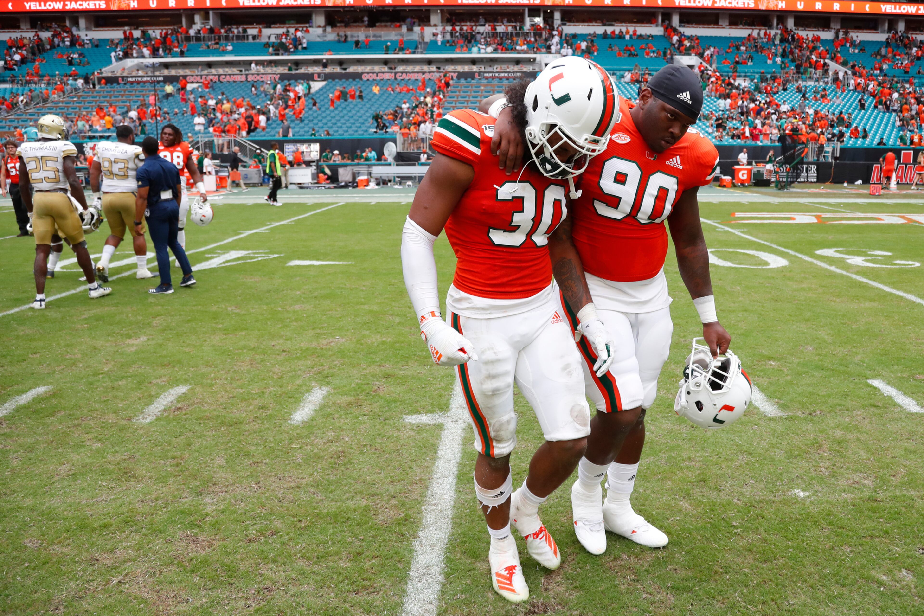 Miami defensive lineman Tyreic Martin (90) consoles linebacker Romeo Finley (30) as they walk off the field after an NCAA college football game against Georgia Tech, Saturday, Oct. 19, 2019, in Miami Gardens, Fla. Georgia Tech defeated Miami 28-21 in overtime. (AP Photo/Wilfredo Lee)