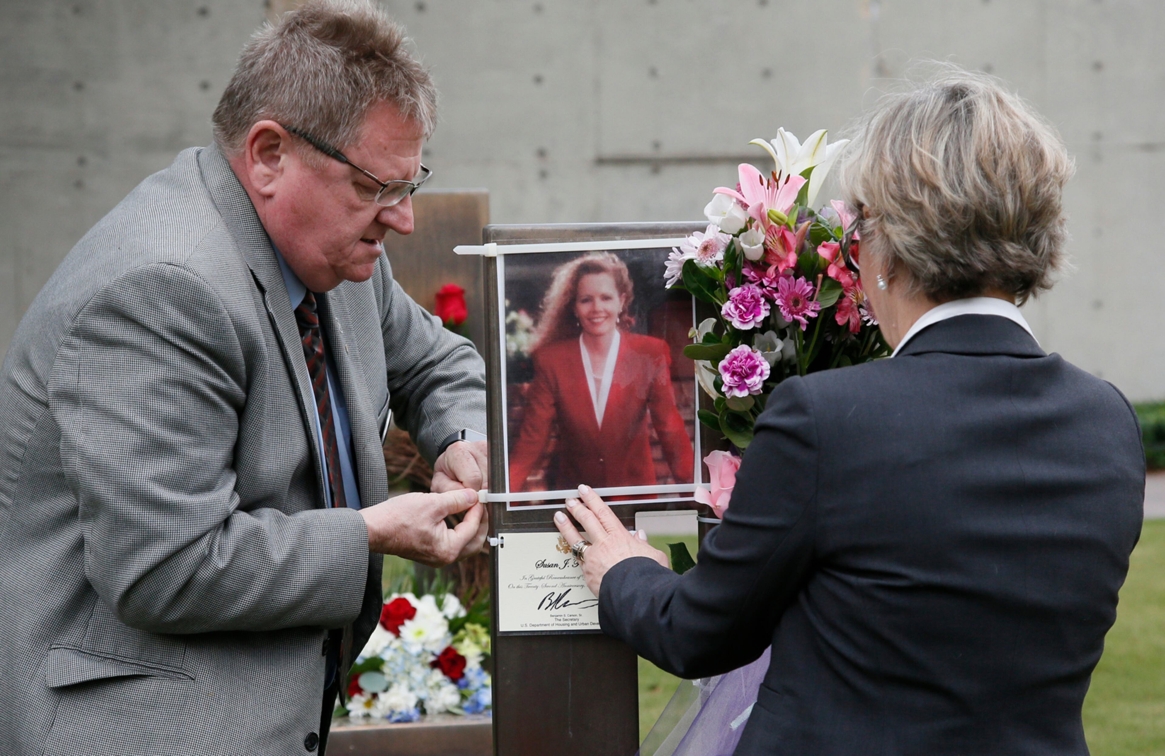 Albert Ashwood, left, and Cindy Ferrell Ashwood affix a photograph of Susan Jane Ferrell to her chair in the Field of Chairs at the Oklahoma City memorial in Oklahoma City, Wednesday, April 19, 2017, on the 22nd anniversary of the Oklahoma City bombing. Cindy Ferrell Ashwood and Susan Jane Ferrell are sisters. (AP Photo/Sue Ogrocki)