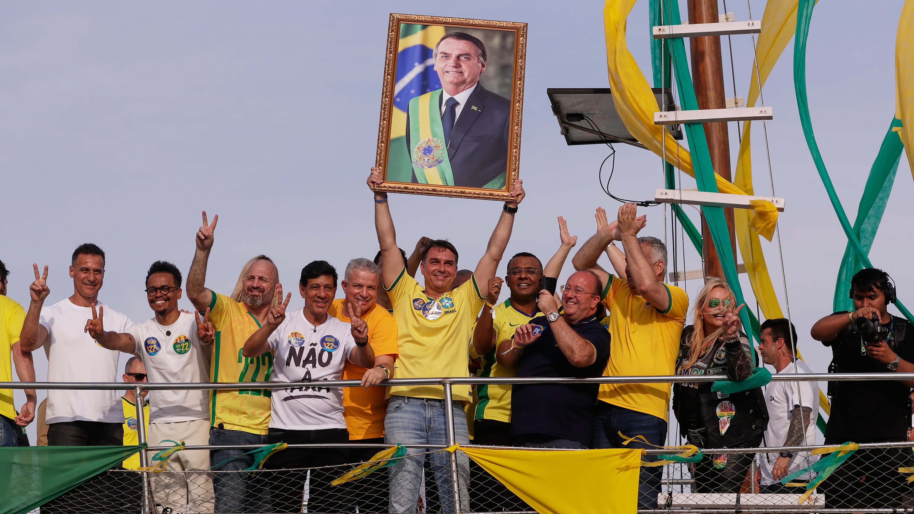 Opposition presidential candidate Flavio Bolsonaro holds a photo of his father, former President Jair Bolsonaro, as he rides a boat during a campaign rally ahead of the October general elections in Angra dos Reis, Rio de Janeiro state, Brazil, Saturday, Aug. 29, 2026. (AP Photo/Bruna Prado)