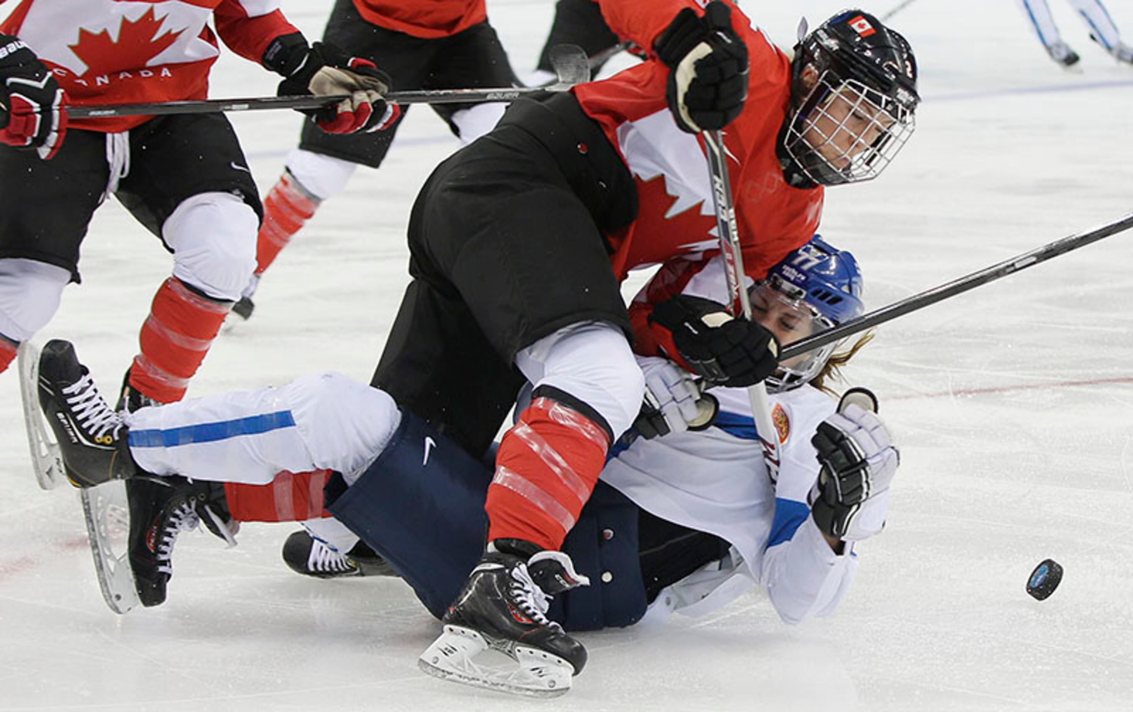 Susanna Tapani of Finland falls as she challenges Meghan Agosta-Marciano of Canada for control of the puck during the third period of the 2014 Winter Olympics women's ice hockey game at Shayba Arena, Monday, Feb. 10, 2014, in Sochi, Russia.