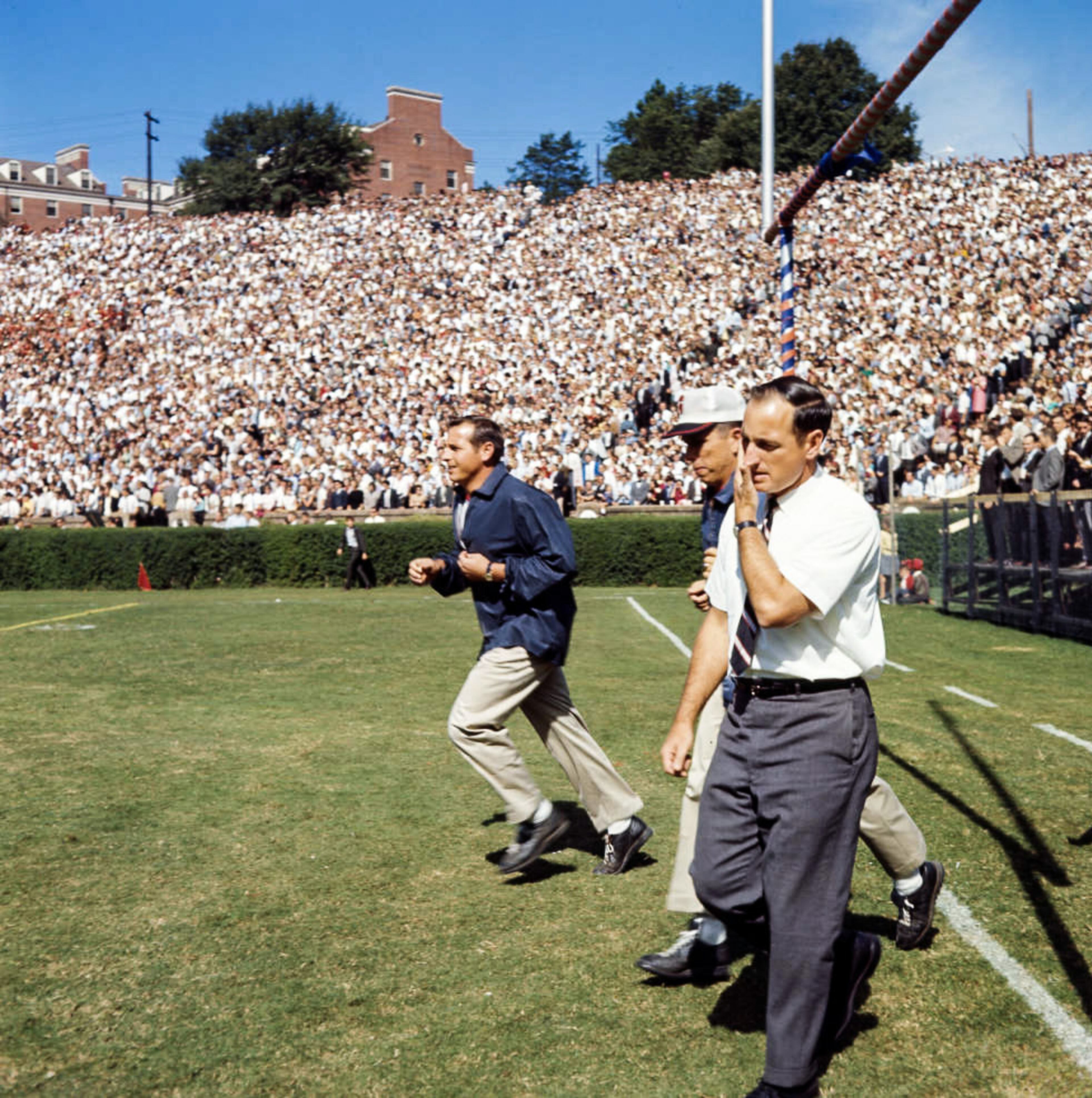 Coach Vince Dooley, assistant coach Bill Dooley and staff run out onto Sanford Stadium's field, 1965