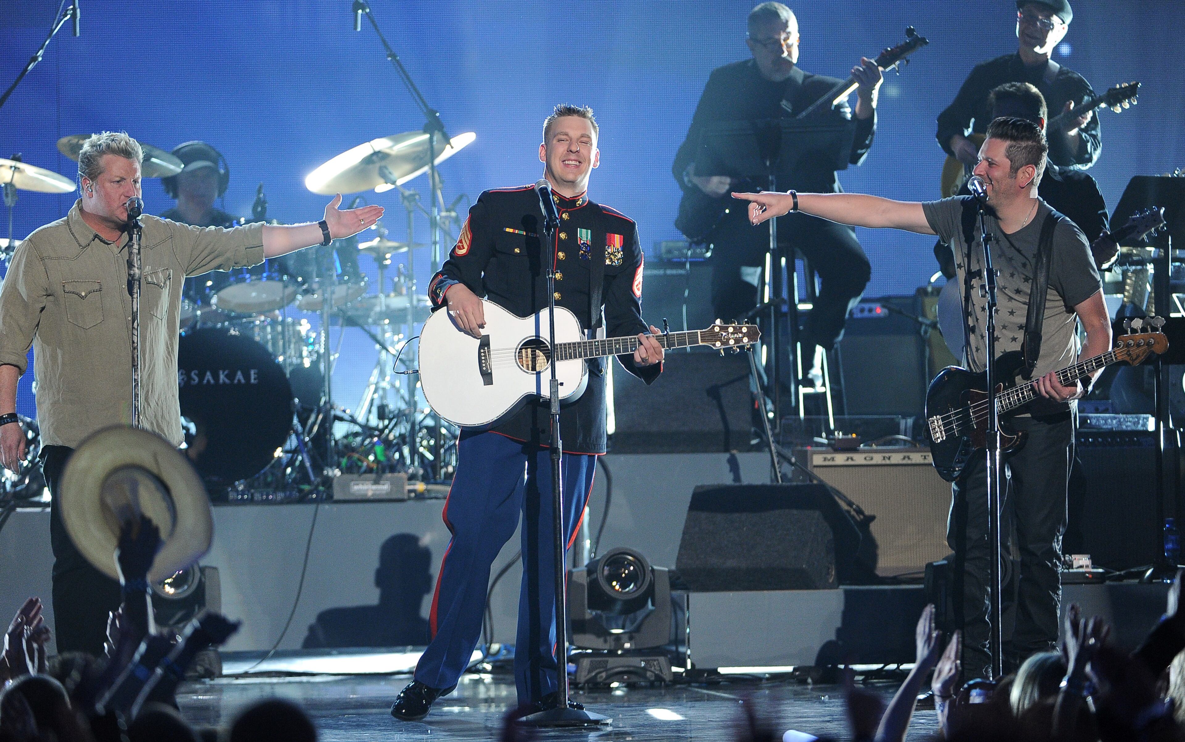 Brandon Valentine, of the U.S. Marine Corps, center, and from left, Gary LeVox and Jay DeMarcus, of the musical group Rascal Flatts, perform at ACM Presents an All-Star Salute to the Troops on Monday, April 7, 2014, in Las Vegas. (Photo by Chris Pizzello/Invision/AP)