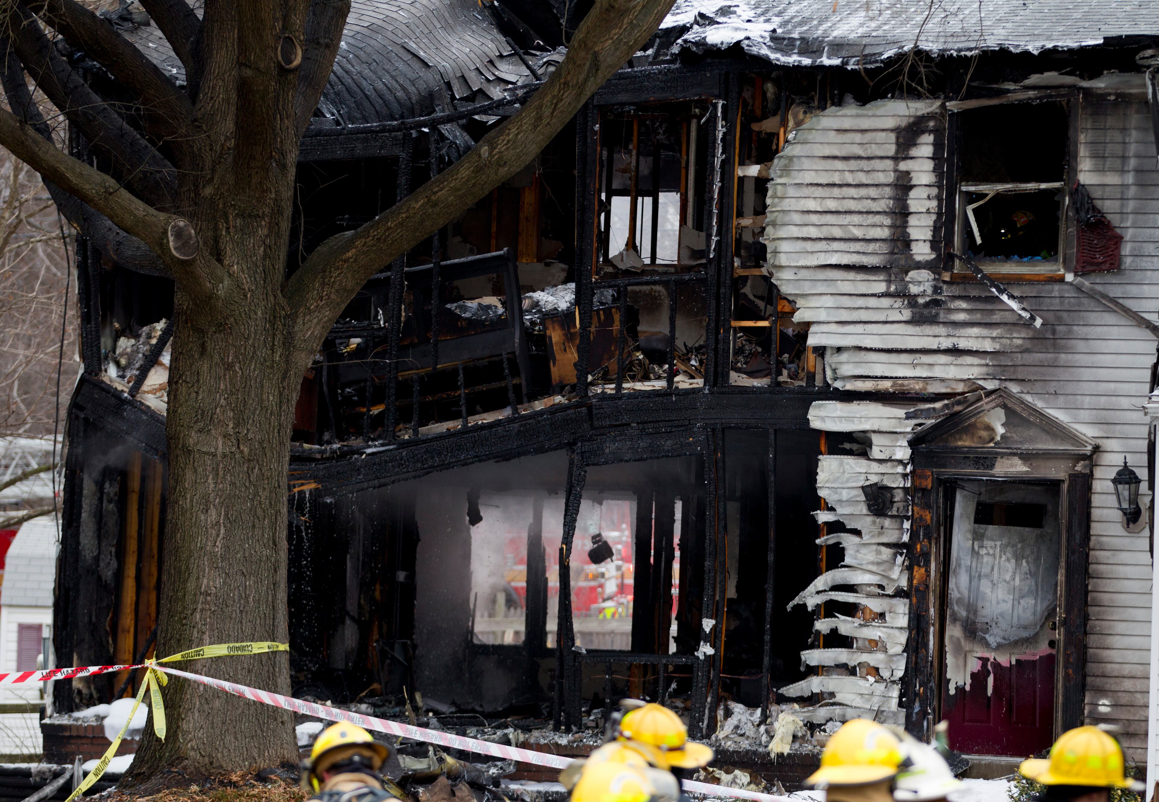 Firefighters stand outside a smoking house where a small plane crashed in Gaithersburg, Md., Monday Dec. 8, 2014. A small, private jet has crashed into a house in Maryland's Montgomery County, and a fire official says multiple people were killed. (AP Photo/Jose Luis Magana)