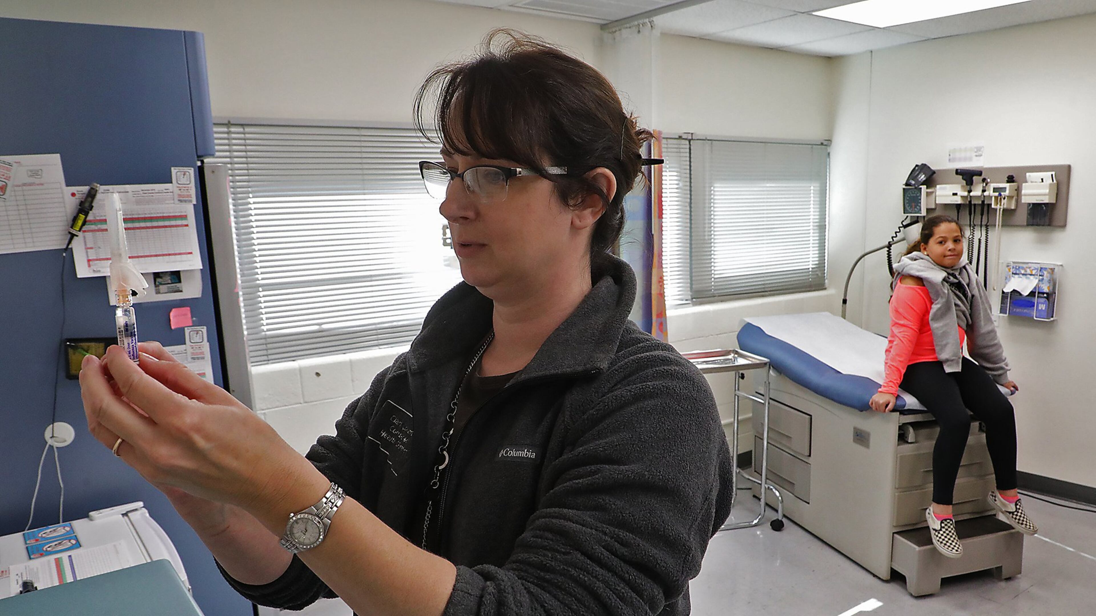 Kristen Earley, a nurse at the Clark County Combined Health District, gets a flu shot ready for Braylinne Muhammad, 11, at the Health District offices. BILL LACKEY/STAFF
