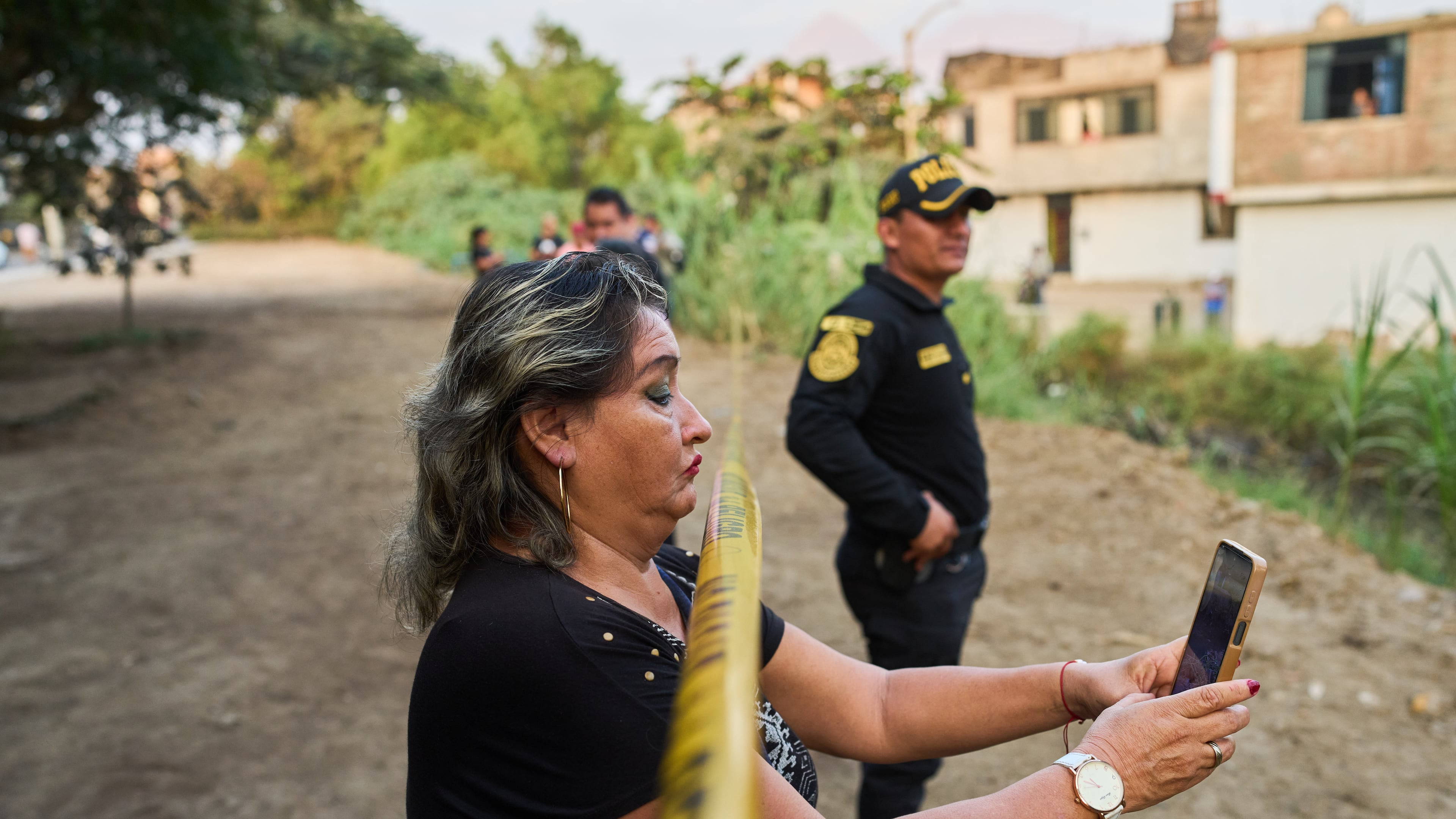 A neighbor records the scene with a cellphone as police recover the body of Jose Perez from a ravine where he was found shot in Trujillo, Peru, Friday, May 30, 2026. (AP Photo/Rodrigo Abd)