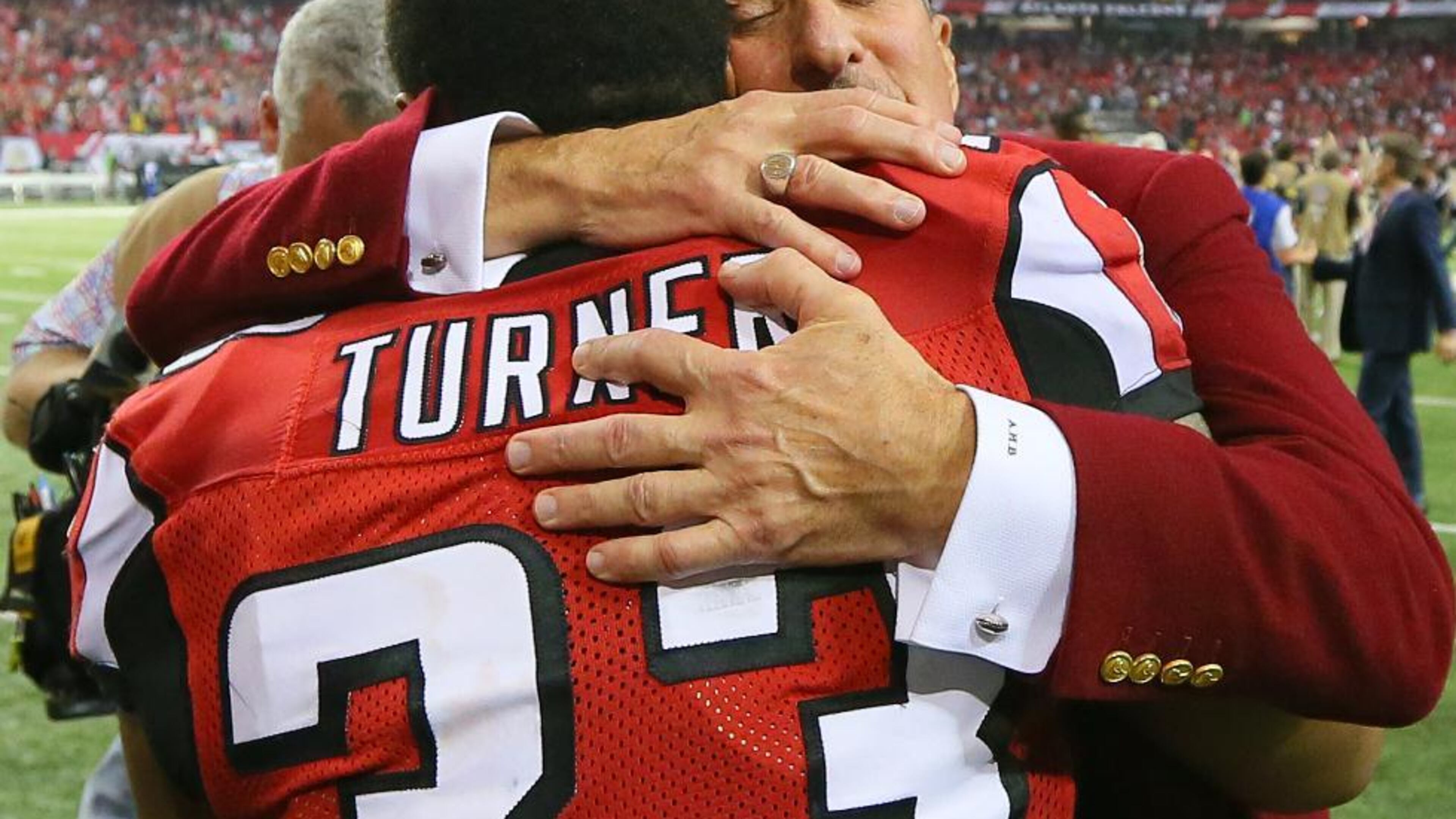 Arthur Blank embraces running back Michael Turner after experiencing a roller-coaster of emotions in the Falcons' playoff win.