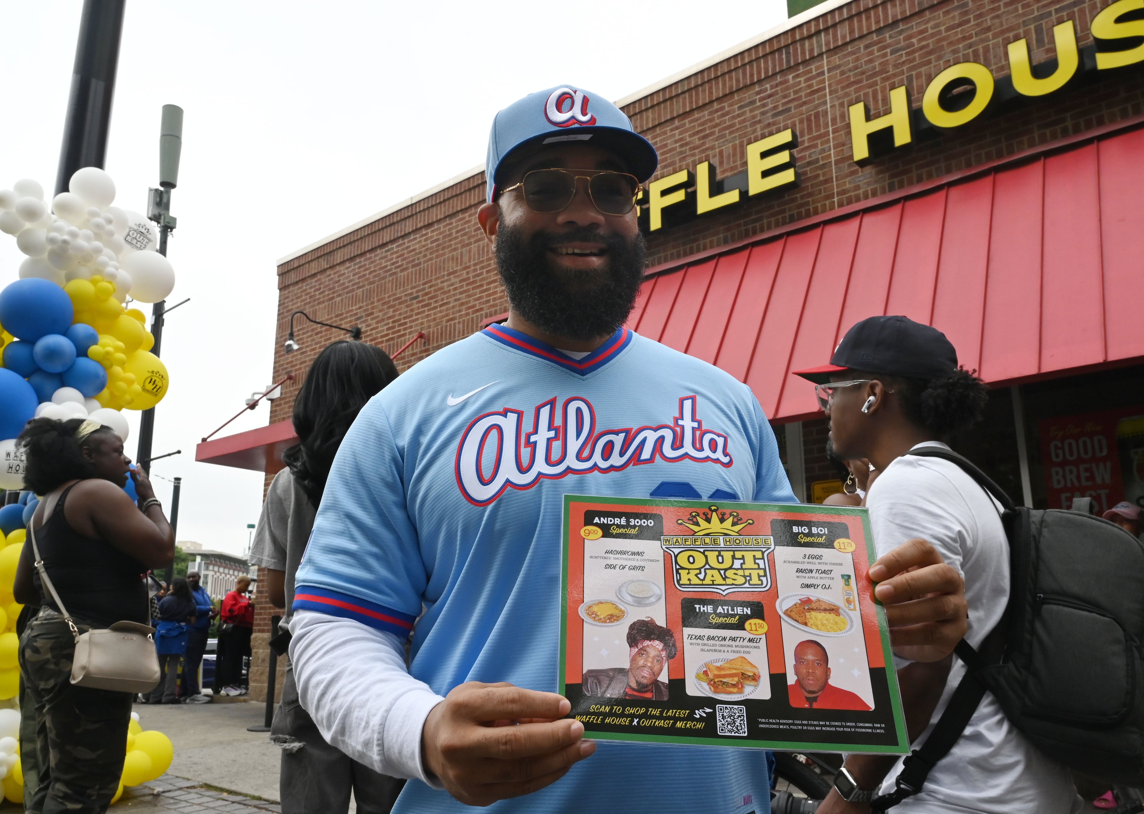 Mark Jacobs holds a souvenir food menu from the Outkast and Waffle House collaboration during an exclusive launch event at the Centennial Olympic Park Waffle House on Friday, Oct. 2, 2026, in Atlanta. (Hyosub Shin/AJC)