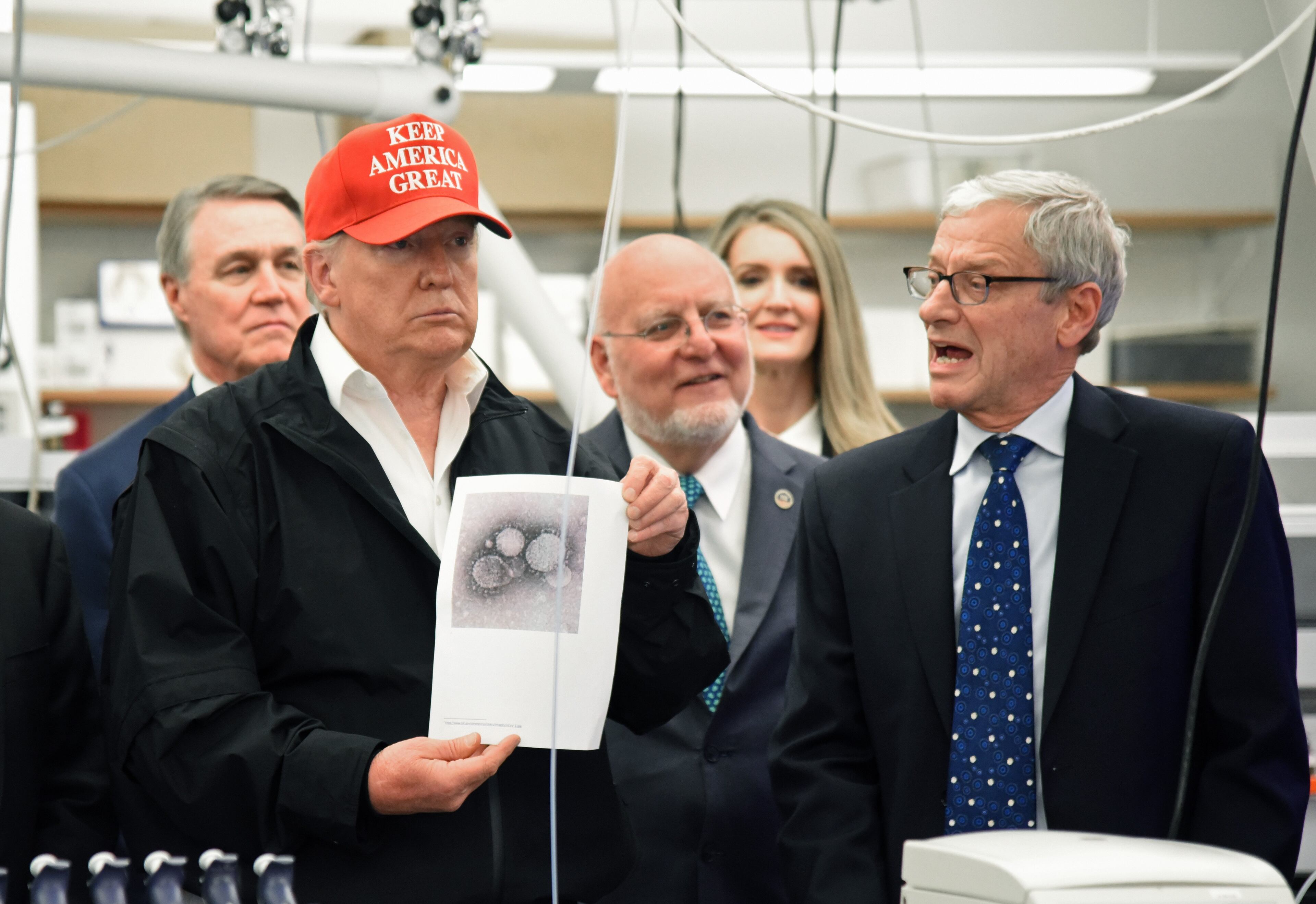 President Donald Trump holds a photograph of the novel coronavirus as Dr. Steve Monroe, right, speaks to the news media during the president's visit to the Centers for Disease Control and Prevention on March 6, 2020. (Hyosub Shin / Hyosub.Shin@ajc.com)