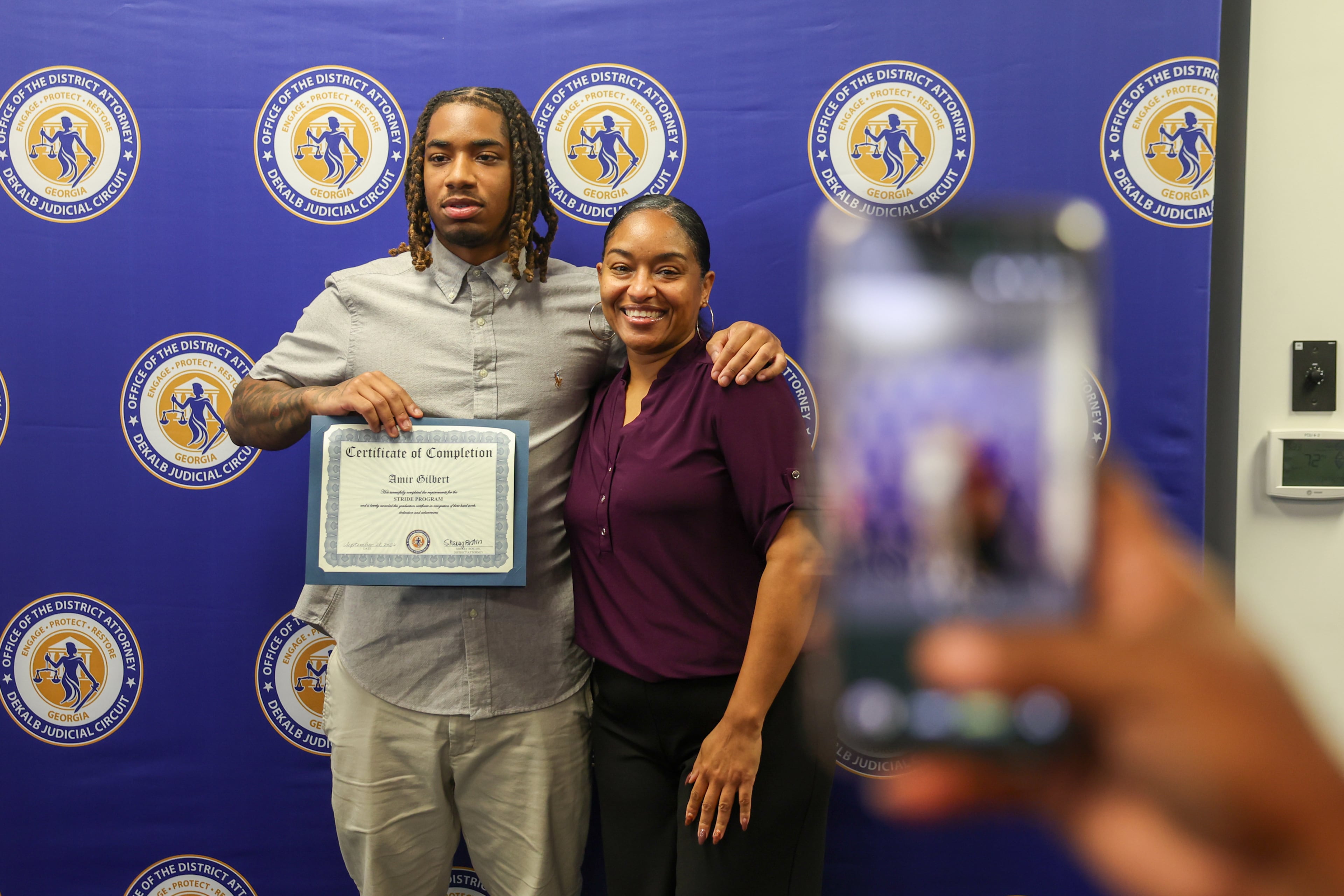 Amir Gilbert poses for a picture with his mother, Yuena Perez, during the STRIDE graduation ceremony on Monday, Sept. 28, 2026, in Decatur. Gilbert now works as a customer care representative with DeKalb County’s sanitation department. (Arvin Temkar/AJC)