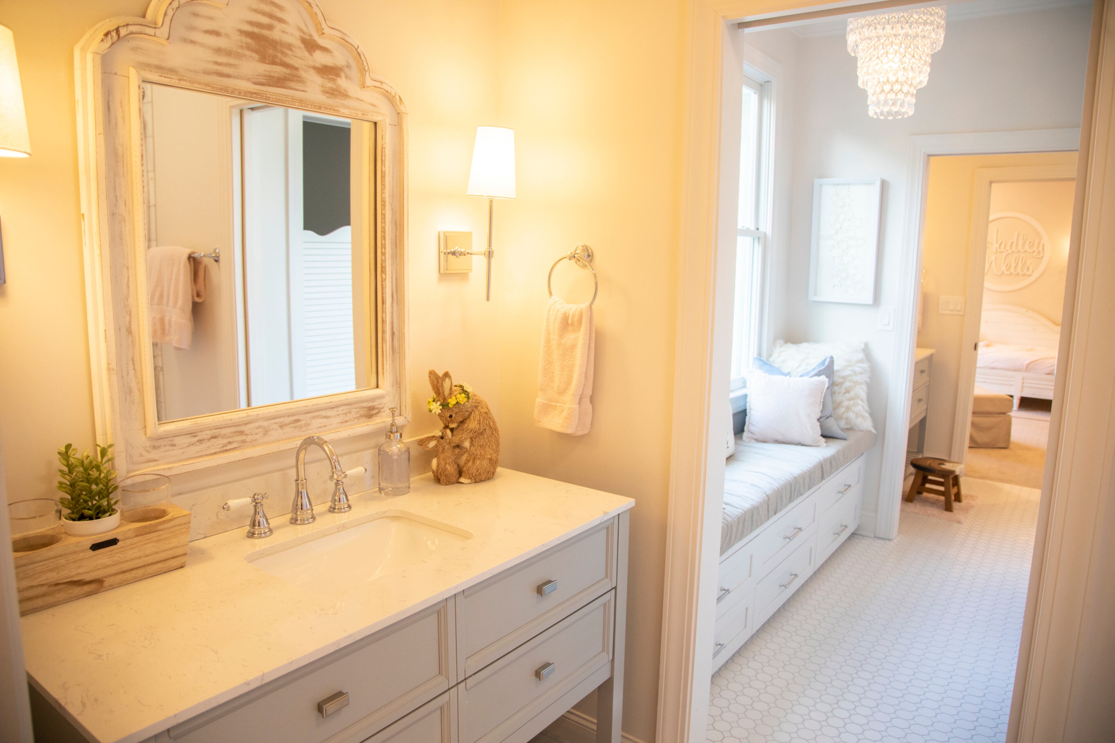In the girls' bathrooms, the vanities and floor tile are from Lowe's and the mirrors from HomeGoods. A chandelier from PBteen marks the center of the shared bathrooms. The wall sconces are from Pottery Barn.
