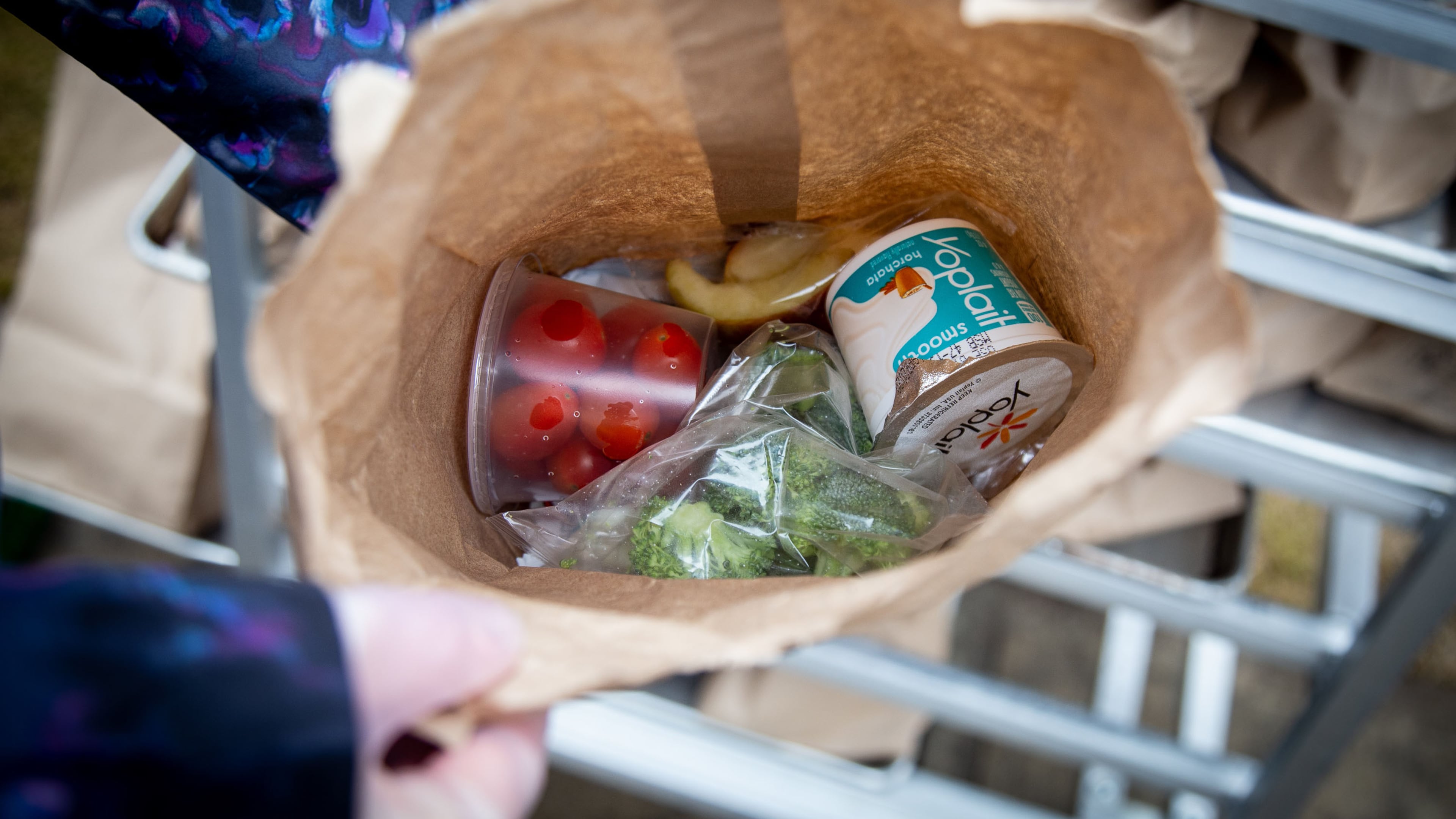 Lilburn Elementary School office worker Lucy Torp holds one of the free lunches that was given out to anyone under 18 on March 16. Gwinnett County and Gwinnett County Public Schools are teaming up to help ease hardships during the COVID-19 pandemic by continuing to feed Gwinnett’s children during the summer. STEVE SCHAEFER / SPECIAL TO THE AJC