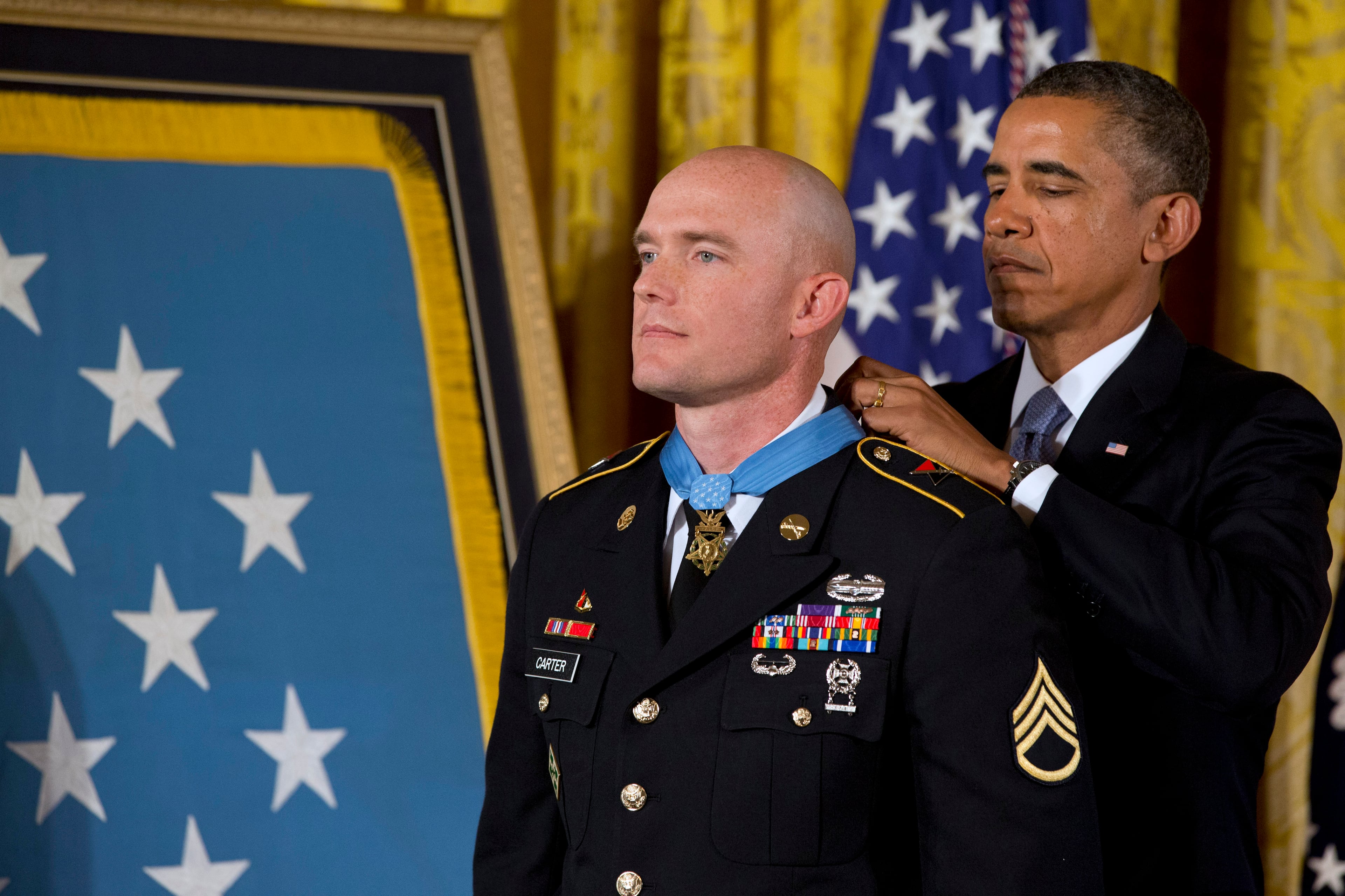 President Barack Obama awards US Army Staff Sgt. Ty M. Carter the Medal of Honor for conspicuous gallantry, Monday, Aug. 26, 2013, during a ceremony in the East Room of the White House in Washington. Carter received the medal for his courageous actions while serving as a cavalry scout with Bravo Troop, 3rd Squadron, 61st Cavalry Regiment, 4th Brigade Combat Team, 4th Infantry Division, during combat operations in Kamdesh District, Nuristan Province, Afghanistan on Oct. 3, 2009. Carter is the fifth living recipient to be awarded the Medal of Honor for actions in Iraq or Afghanistan. (AP Photo/Jacquelyn Martin)