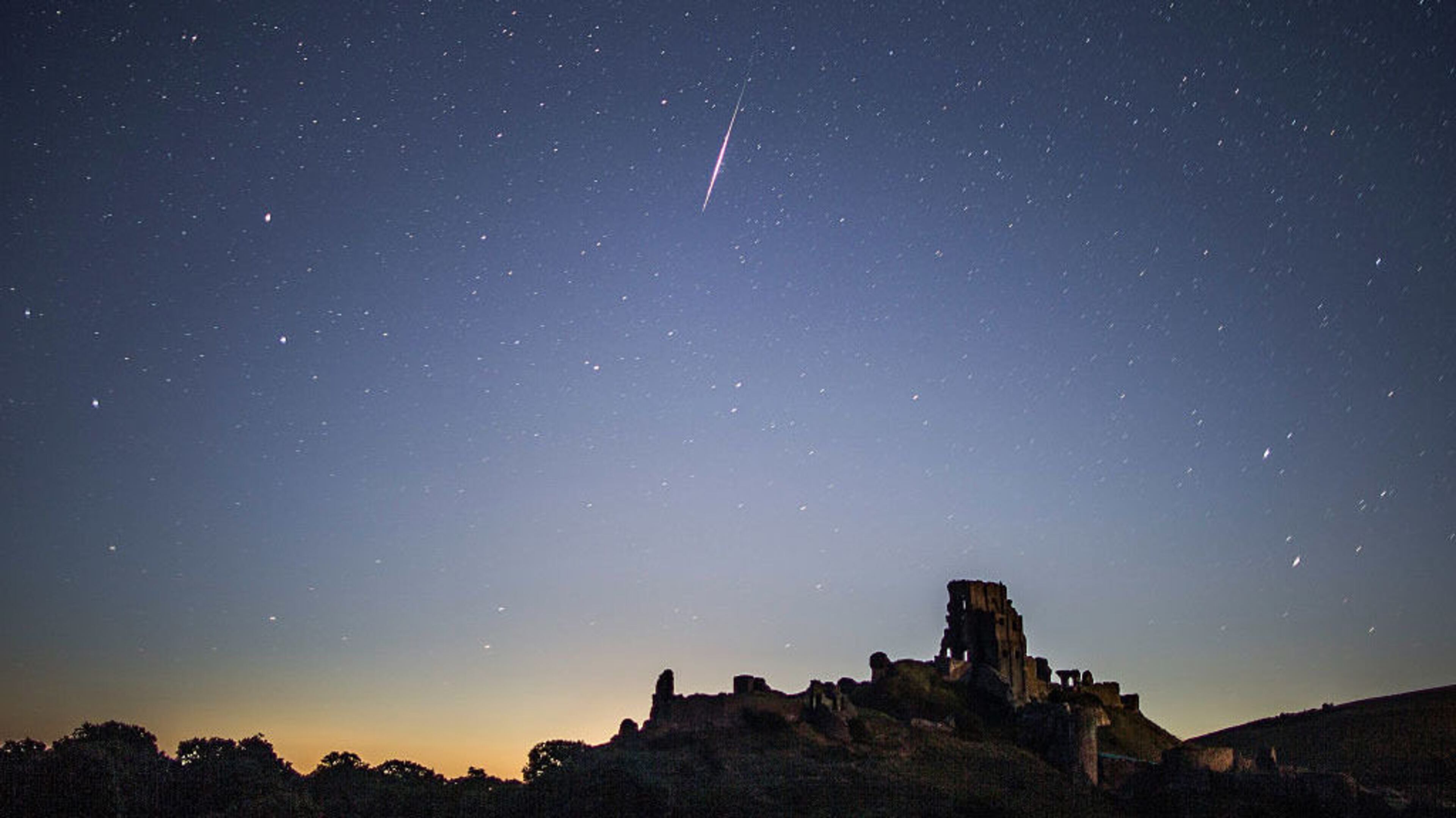 A Perseid meteor flashes across the night sky above Corfe Castle on August 12, 2016 in Corfe Castle, United Kingdom. The Perseids meteor shower occurs every year when the Earth passes through the cloud of debris left by Comet Swift-Tuttle.