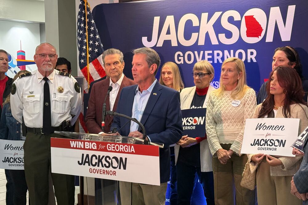 Gov. Brian Kemp (at lectern) and Republican nominee Rick Jackson (to his left) kick off a daylong fly-around tour at Signature Aviation in Atlanta earlier this month. (Greg Bluestein/AJC)