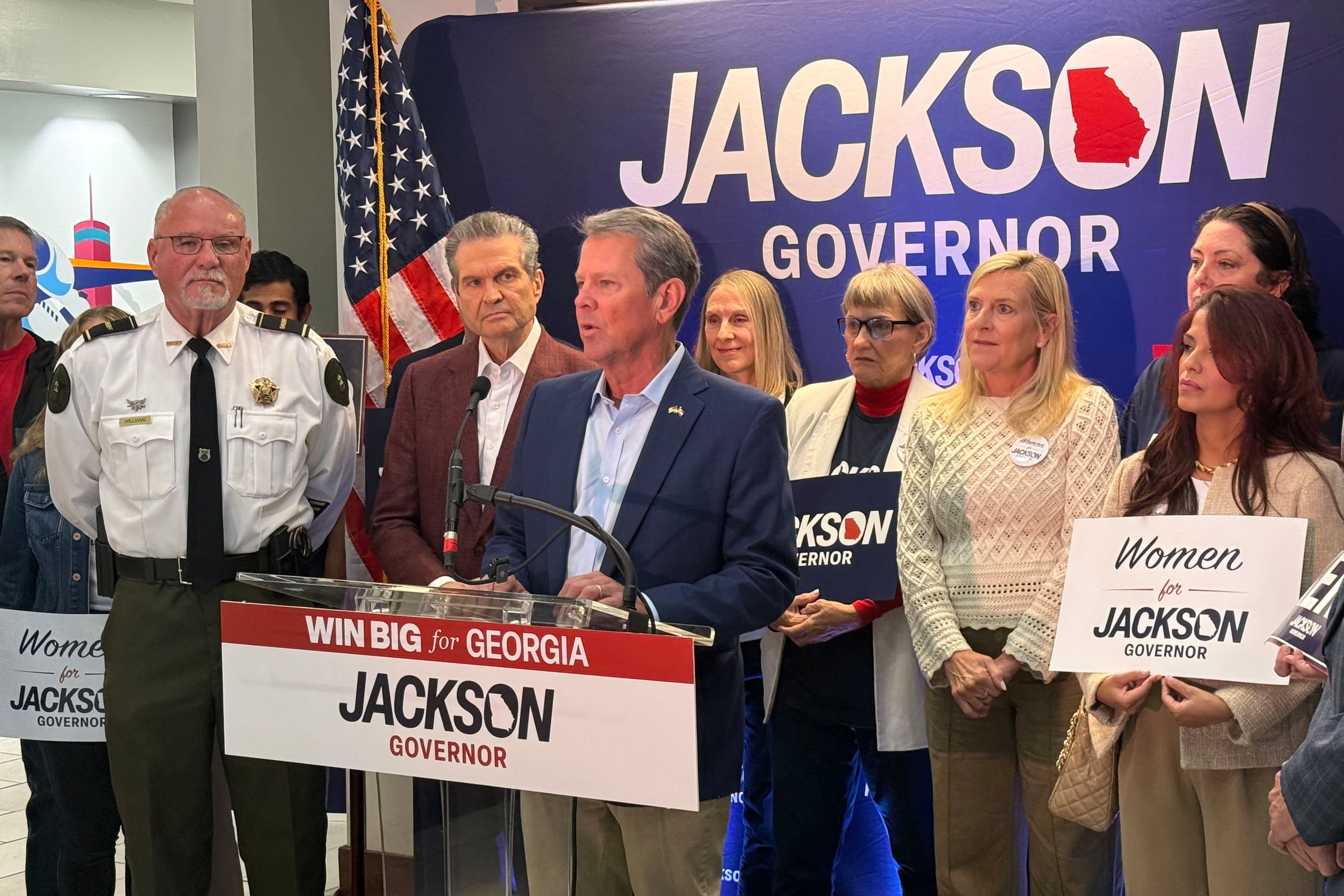 Gov. Brian Kemp (at lectern) and Republican nominee Rick Jackson (to his left) kick off a daylong fly-around tour at Signature Aviation in Atlanta earlier this month. (Greg Bluestein/AJC)