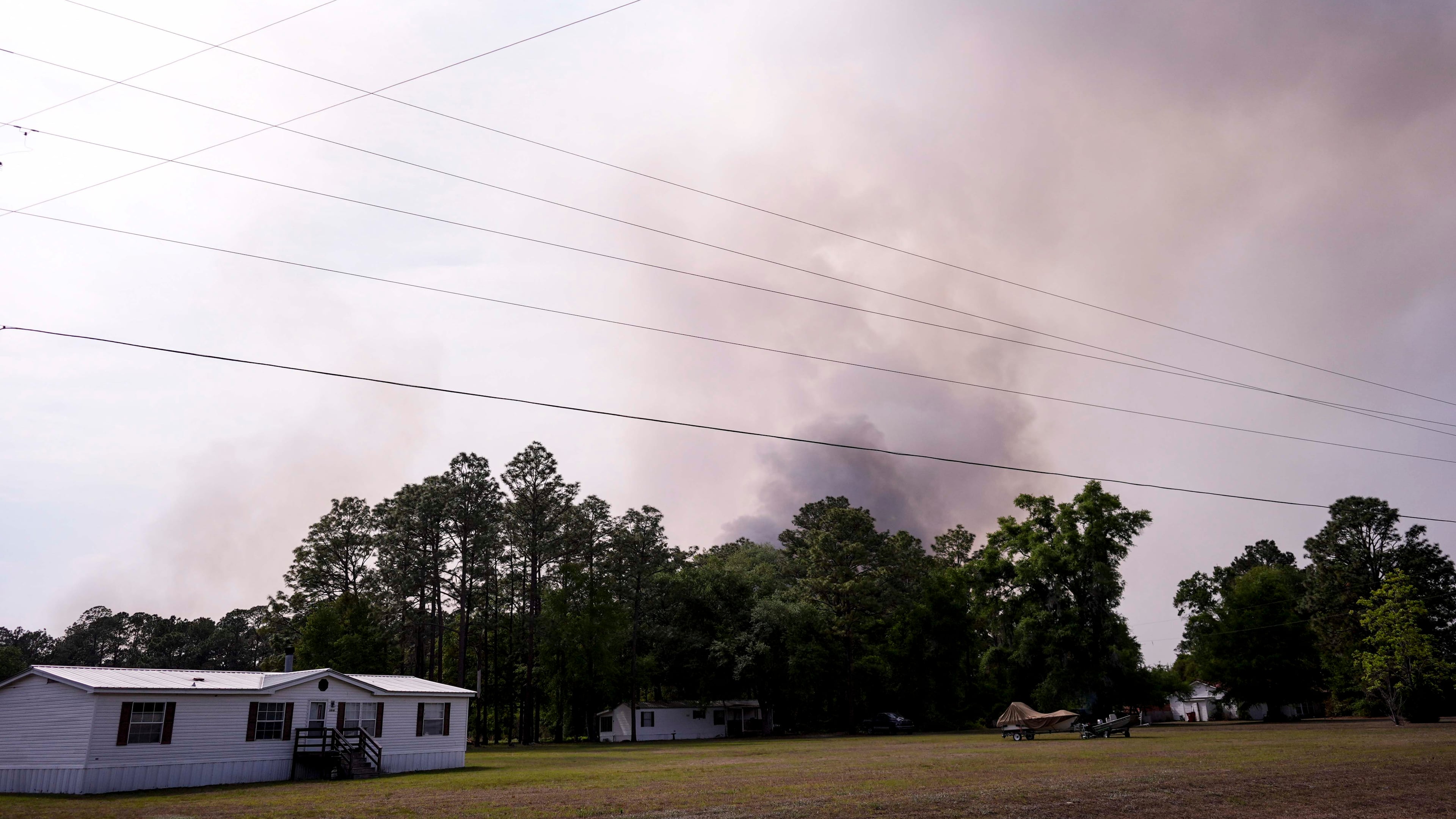 The Pineland road fire in Brantley, county burns behind homes, Wednesday, April 22, 2026, near Nahunta, Ga. (AP Photo/Mike Stewart)