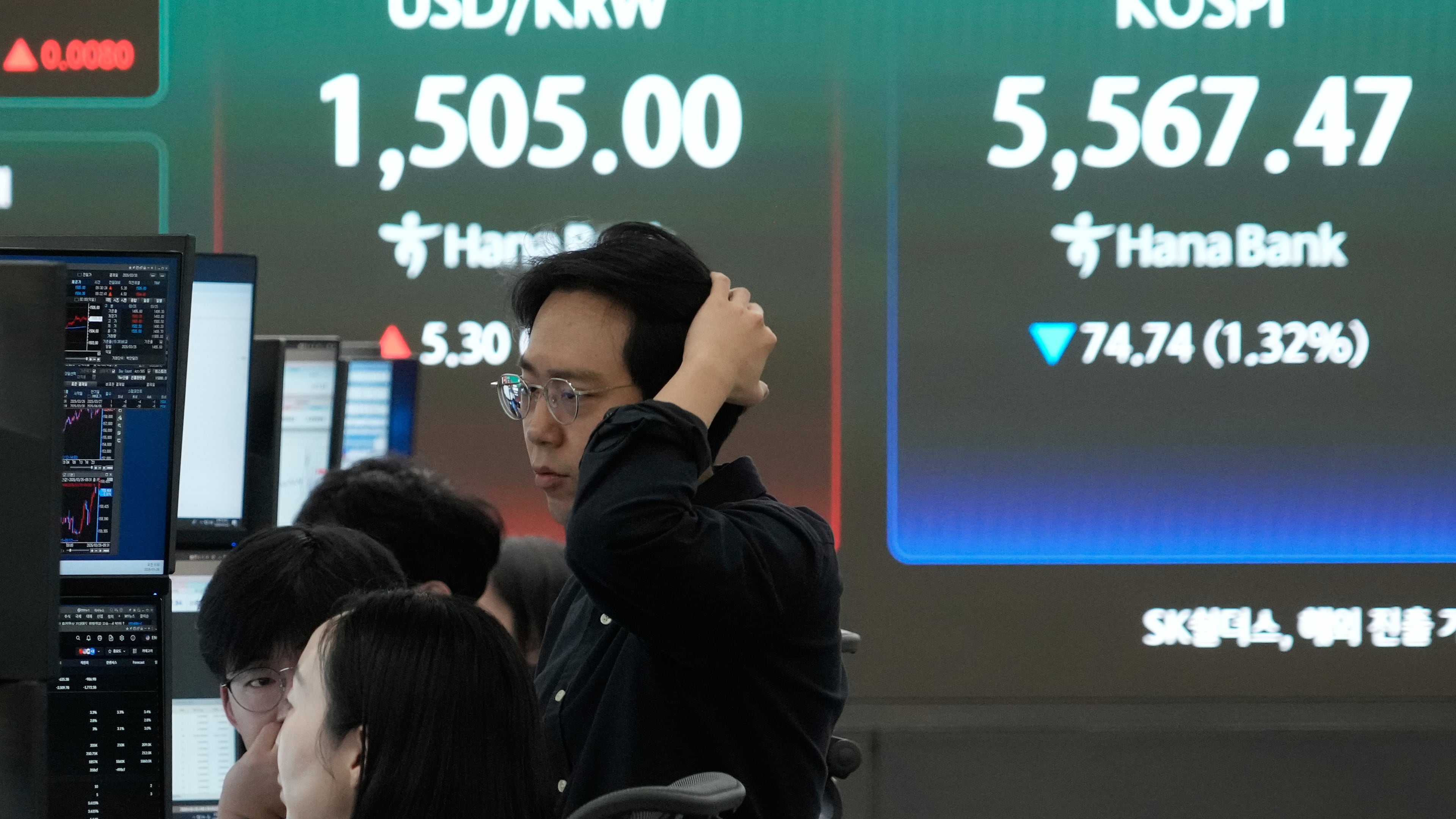 Currency traders watch monitors near a screen showing the Korea Composite Stock Price Index (KOSPI), right, and the foreign exchange rate between U.S. dollar and South Korean won at the foreign exchange dealing room of the Hana Bank headquarters in Seoul, South Korea, Thursday, March 26, 2026. (AP Photo/Ahn Young-joon)